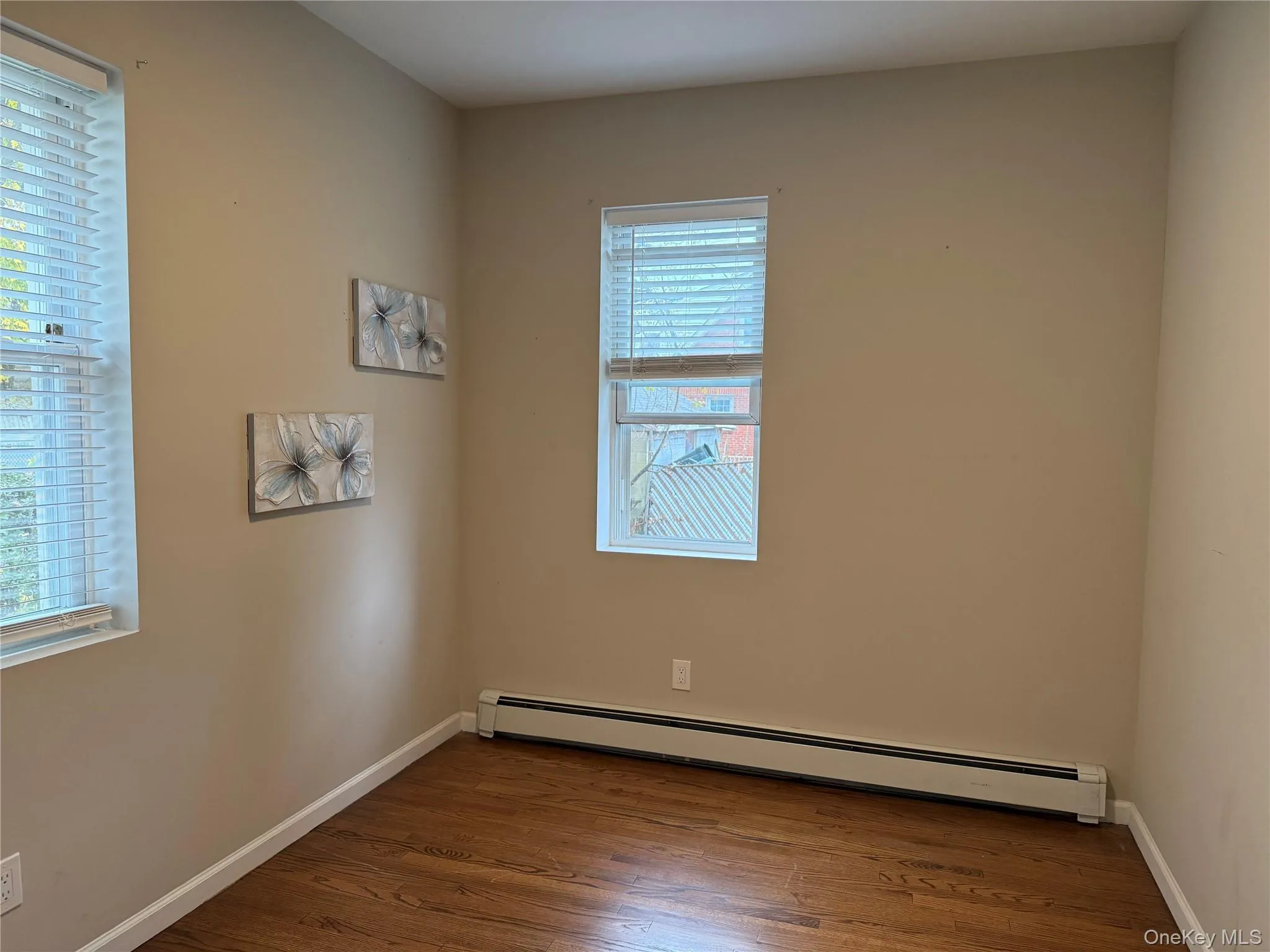 Unfurnished room featuring a baseboard heating unit, dark wood finished floors, and healthy amount of natural light Unfurnished room featuring a baseboard heating unit, dark wood finished floors, and healthy amount of natural light