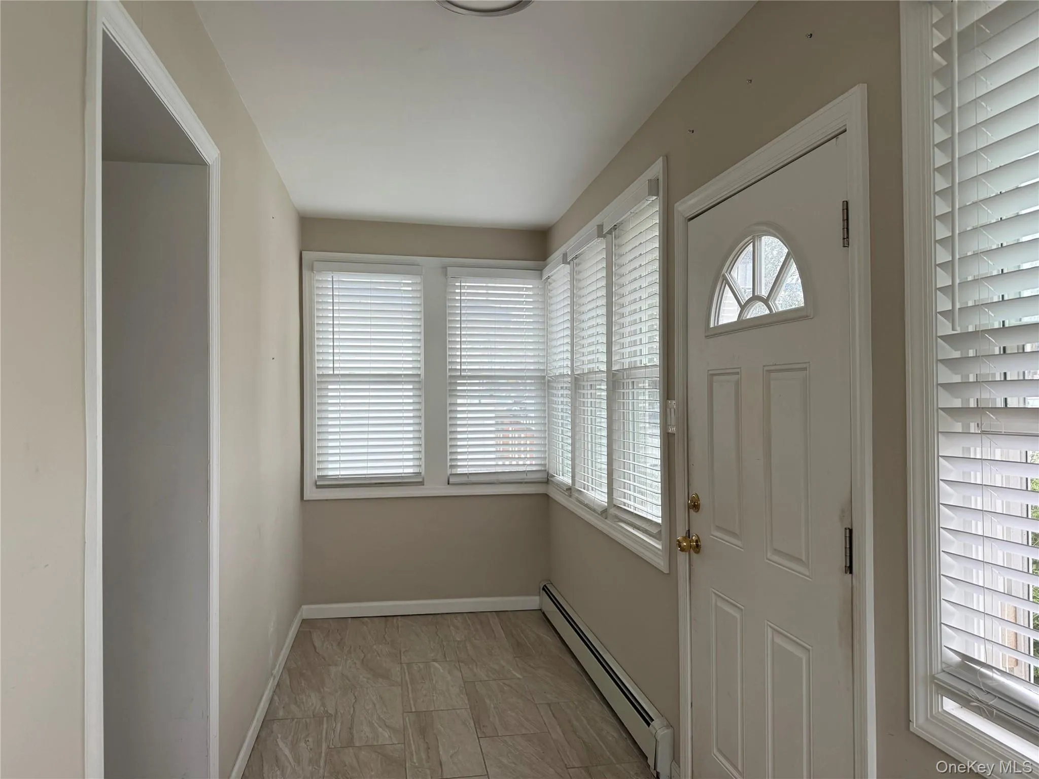 Foyer entrance featuring a baseboard radiator and healthy amount of natural light Foyer entrance featuring a baseboard radiator and healthy amount of natural light
