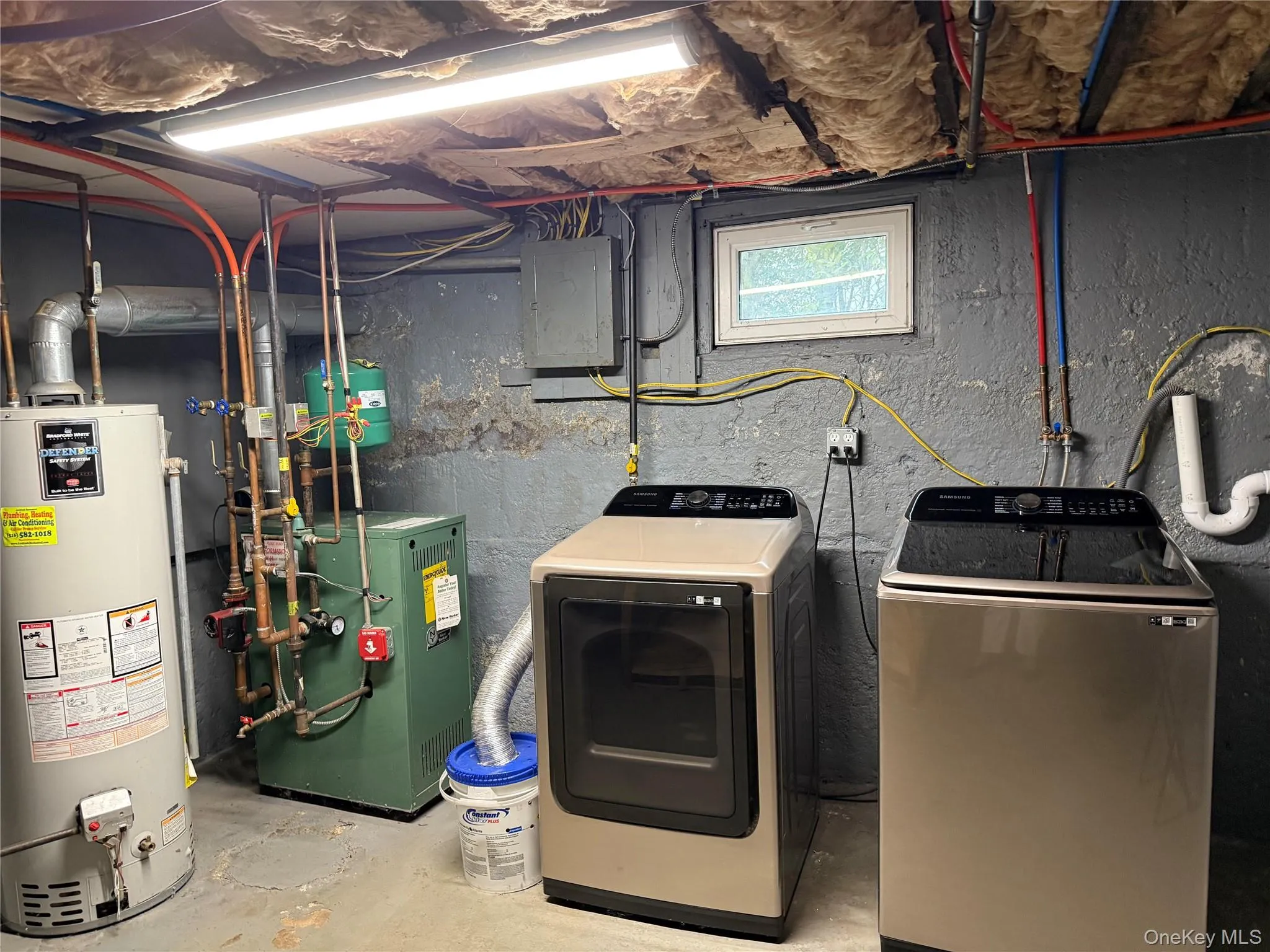 Washroom with gas water heater, concrete floors, electric panel, a heating unit, and independent washer and dryer Washroom with gas water heater, concrete floors, electric panel, a heating unit, and independent washer and dryer