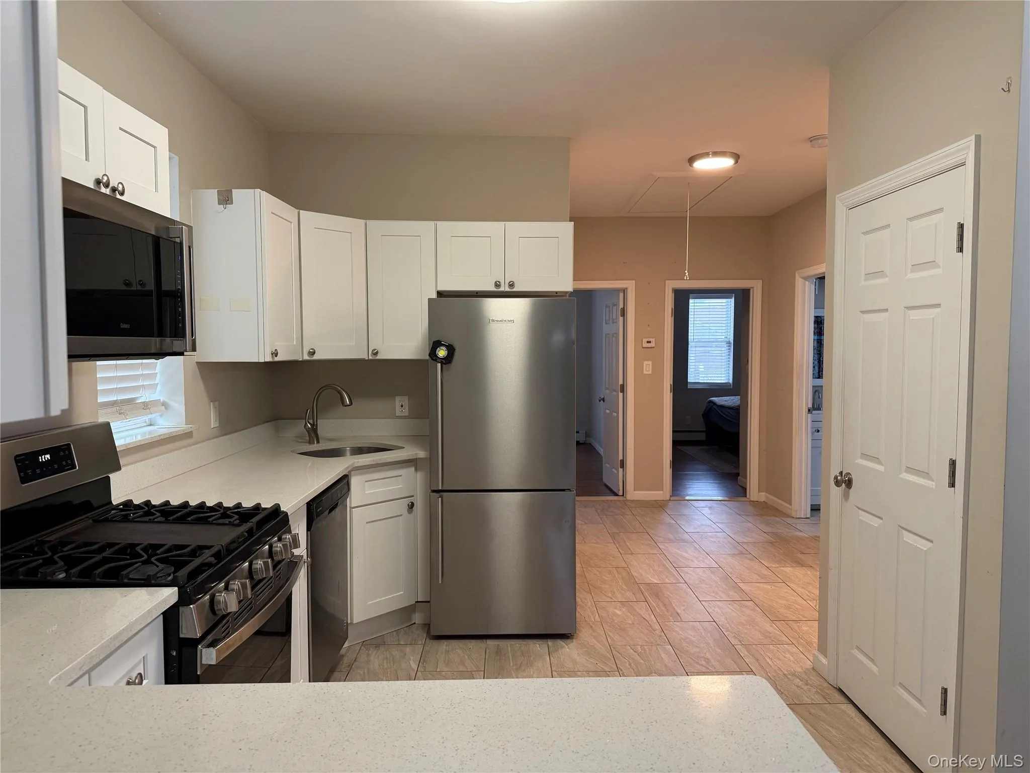 Kitchen featuring stainless steel appliances, white cabinetry, and light stone counters Kitchen featuring stainless steel appliances, white cabinetry, and light stone counters