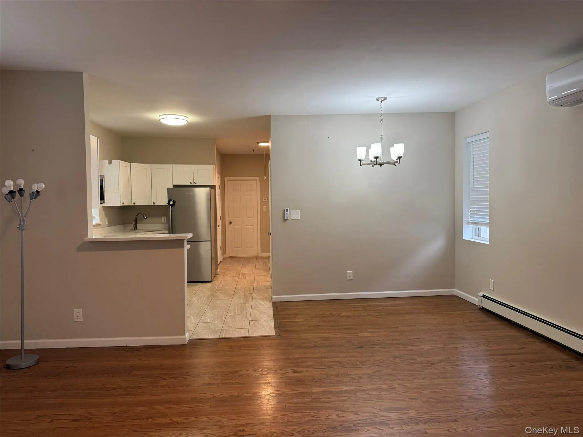 Kitchen with light countertops, freestanding refrigerator, white cabinets, light wood-style floors, and decorative light fixtures Kitchen with light countertops, freestanding refrigerator, white cabinets, light wood-style floors, and decorative light fixtures