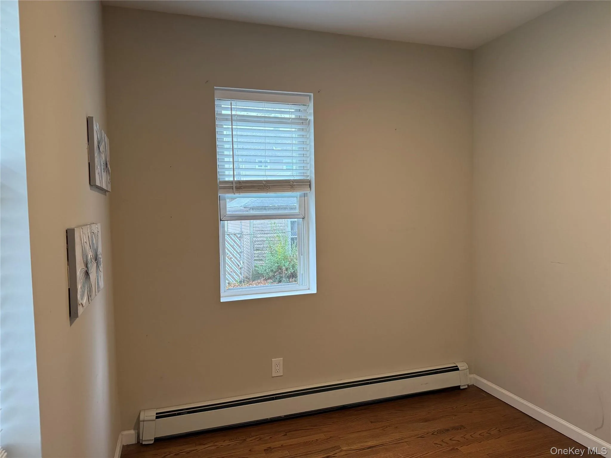Unfurnished room with a baseboard heating unit and dark wood-style flooring Unfurnished room with a baseboard heating unit and dark wood-style flooring