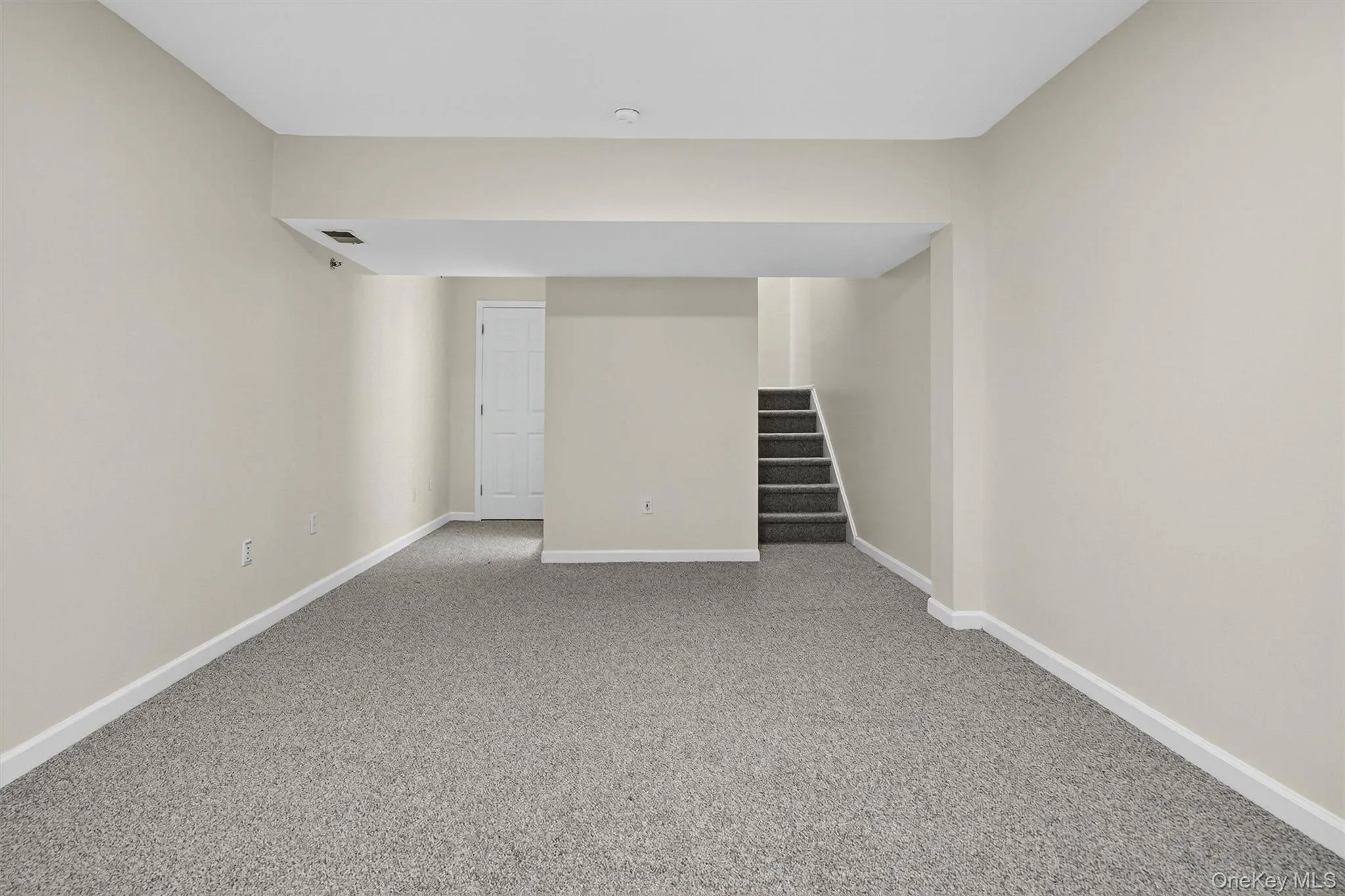 Finished below grade area featuring carpet floors and stairway Finished below grade area featuring carpet floors and stairway