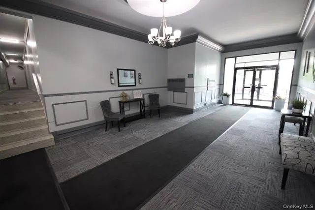 Entryway featuring patterned carpet flooring, wainscoting, and a multi-light chandelier Entryway featuring patterned carpet flooring, wainscoting, and a multi-light chandelier