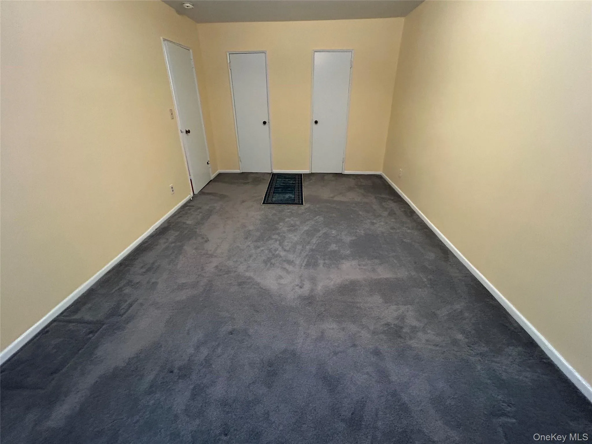 Bedroom featuring light-colored walls and dark gray carpet flooring Bedroom featuring light-colored walls and dark gray carpet flooring