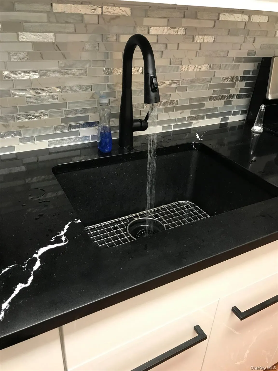 Modern kitchen featuring a farmhouse sink with a matte black high-arc pull down faucet, complemented by a rectangular ceramic tiled backsplash Modern kitchen featuring a farmhouse sink with a matte black high-arc pull down faucet, complemented by a rectangular ceramic tiled backsplash