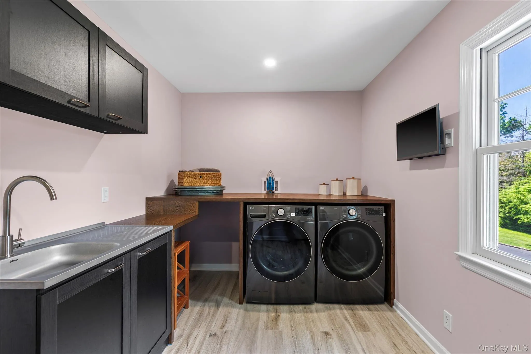 This gorgeous laundry room boasts high-end washer and dryer, a sink, a folding shelf, cabinets, and a full closet for cleaning equipment. This gorgeous laundry room boasts high-end washer and dryer, a sink, a folding shelf, cabinets, and a full closet for cleaning equipment.