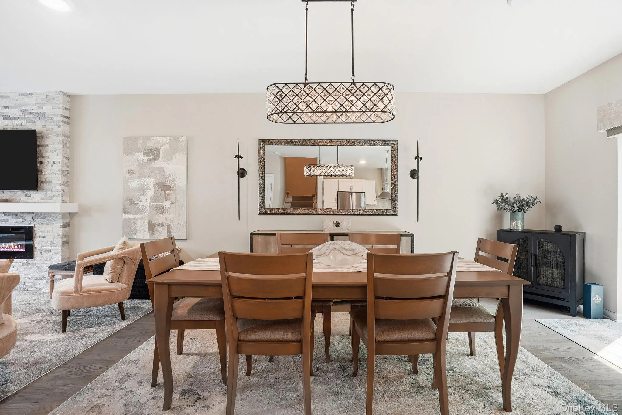 Open-concept dining area featuring wood-finish flooring, an ornate linear chandelier, and neutral wall tones Open-concept dining area featuring wood-finish flooring, an ornate linear chandelier, and neutral wall tones