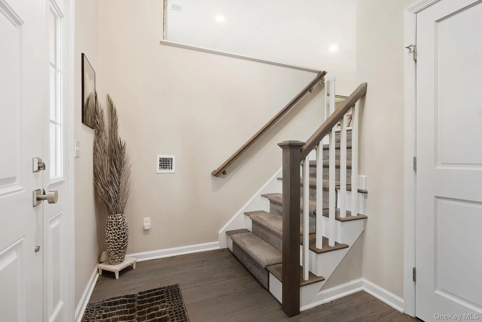 Entryway featuring wood-finish flooring, a staircase with carpeted treads and wood handrail Entryway featuring wood-finish flooring, a staircase with carpeted treads and wood handrail