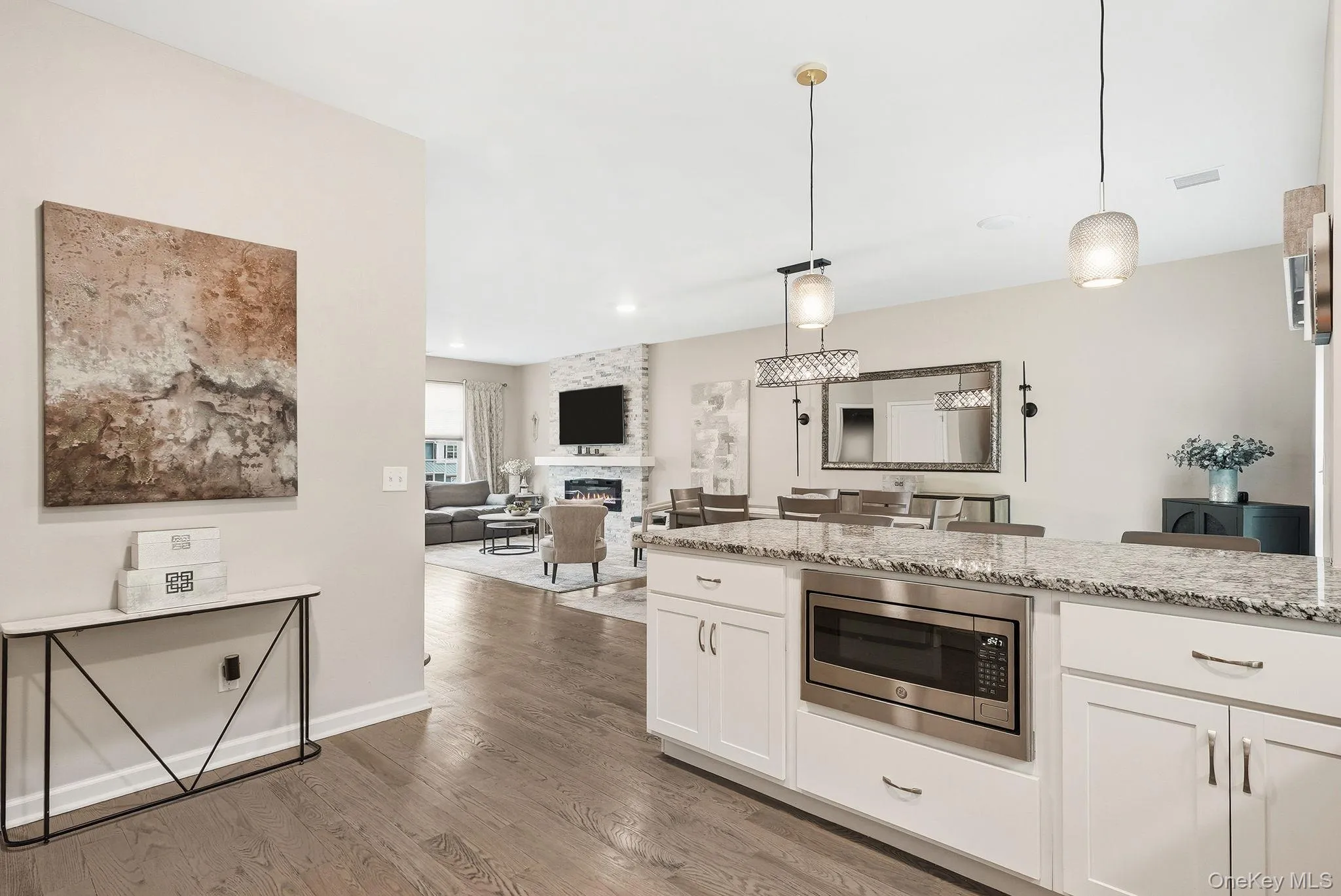 Spacious kitchen island featuring a built-in stainless steel microwave, stone countertop, and white cabinetry Spacious kitchen island featuring a built-in stainless steel microwave, stone countertop, and white cabinetry