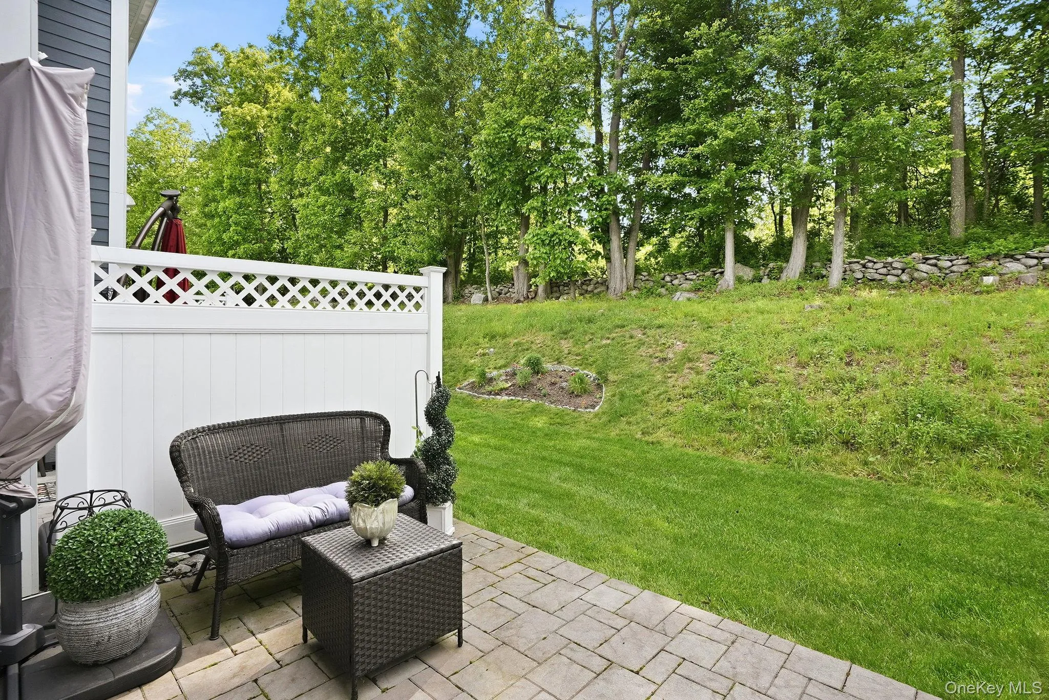 Outdoor grass area with private paver patio and white lattice fencing Outdoor grass area with private paver patio and white lattice fencing