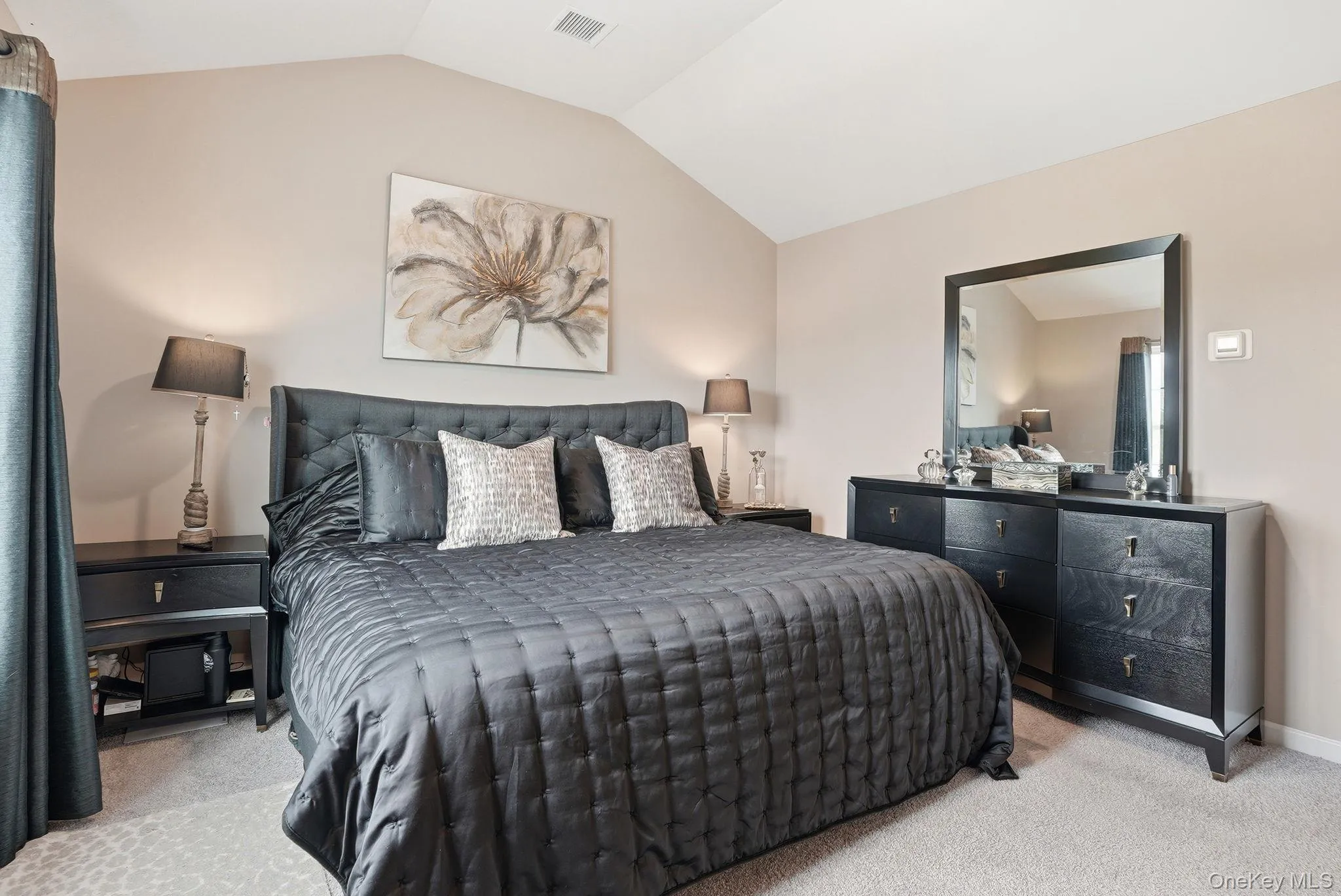 Primary bedroom featuring vaulted ceilings elevate this carpeted bedroom, featuring light beige wall tones Primary bedroom featuring vaulted ceilings elevate this carpeted bedroom, featuring light beige wall tones