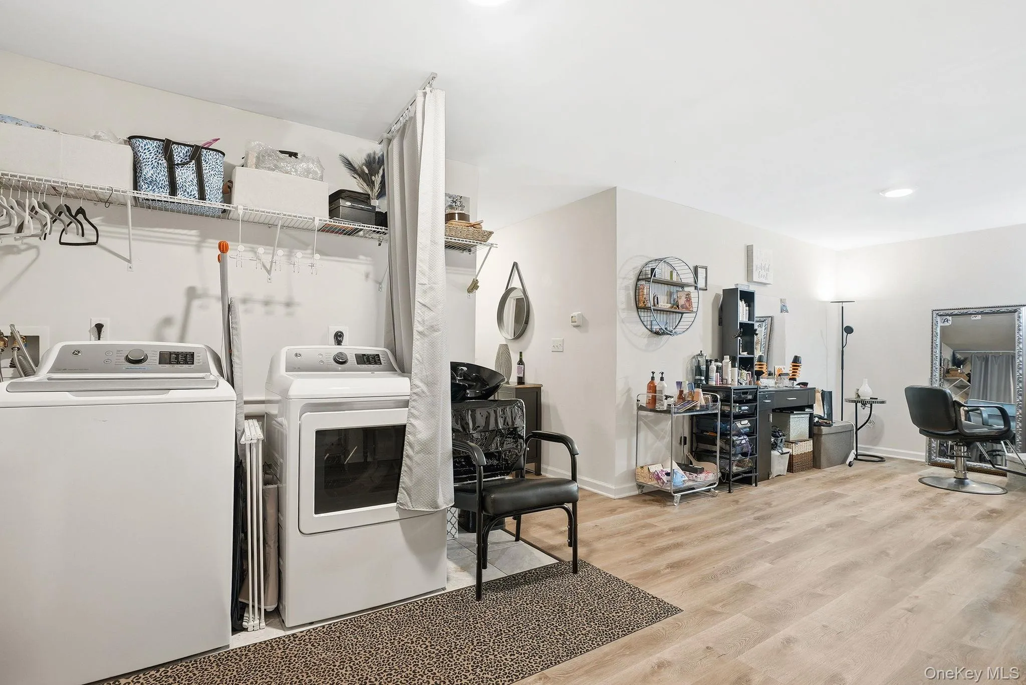 Basement Dedicated laundry area featuring white appliances and integrated wire shelving Basement Dedicated laundry area featuring white appliances and integrated wire shelving