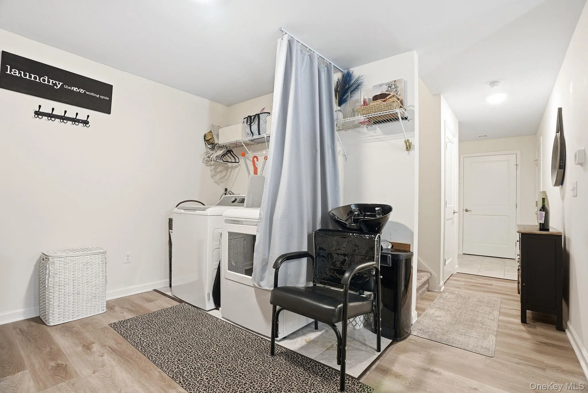 Dedicated laundry area featuring a washer, dryer, built-in shelving, and wood-finish flooring Dedicated laundry area featuring a washer, dryer, built-in shelving, and wood-finish flooring