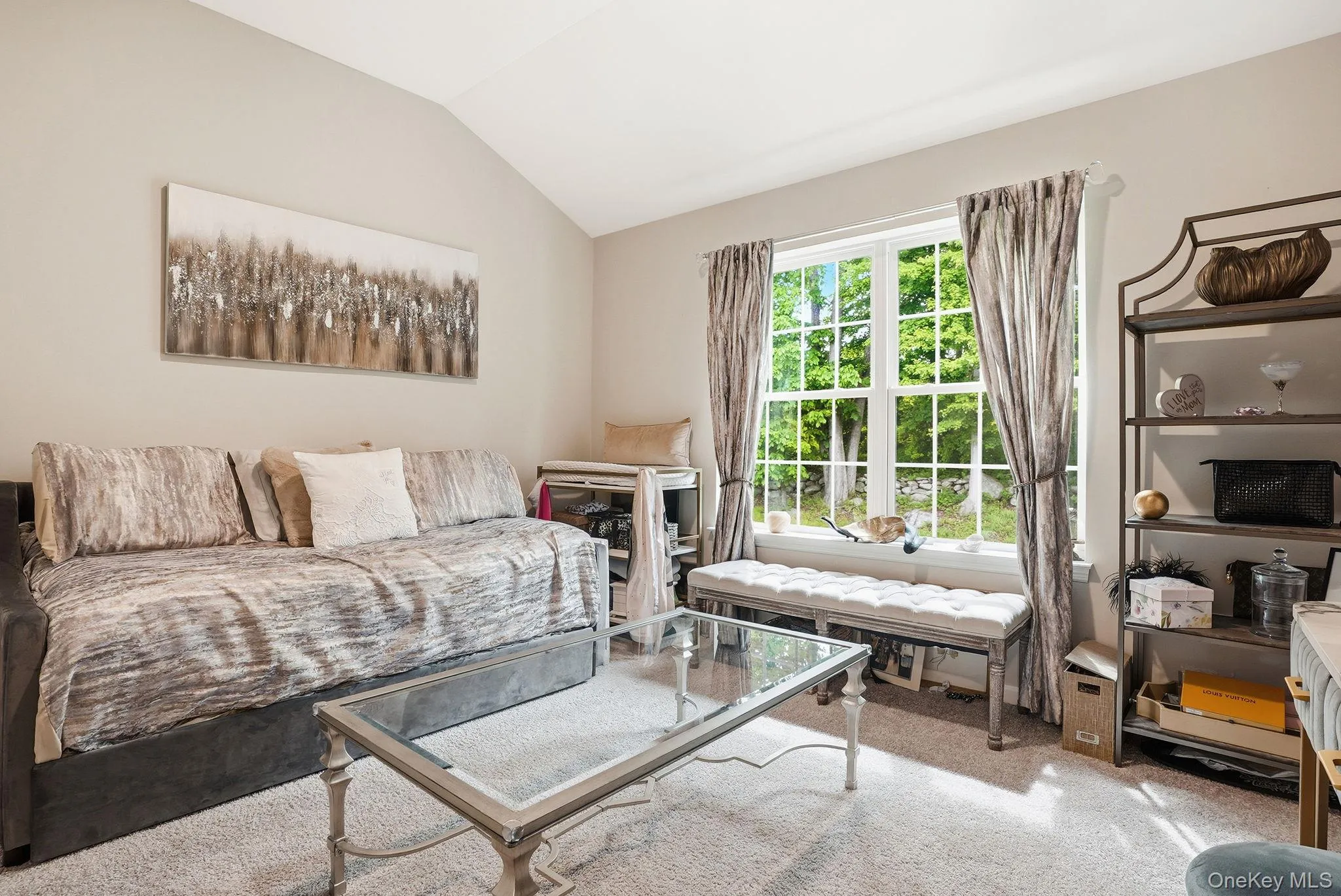 Second bedroom featuring vaulted ceiling room featuring a large multi-pane window, neutral-toned walls, and soft grey carpet flooring Second bedroom featuring vaulted ceiling room featuring a large multi-pane window, neutral-toned walls, and soft grey carpet flooring