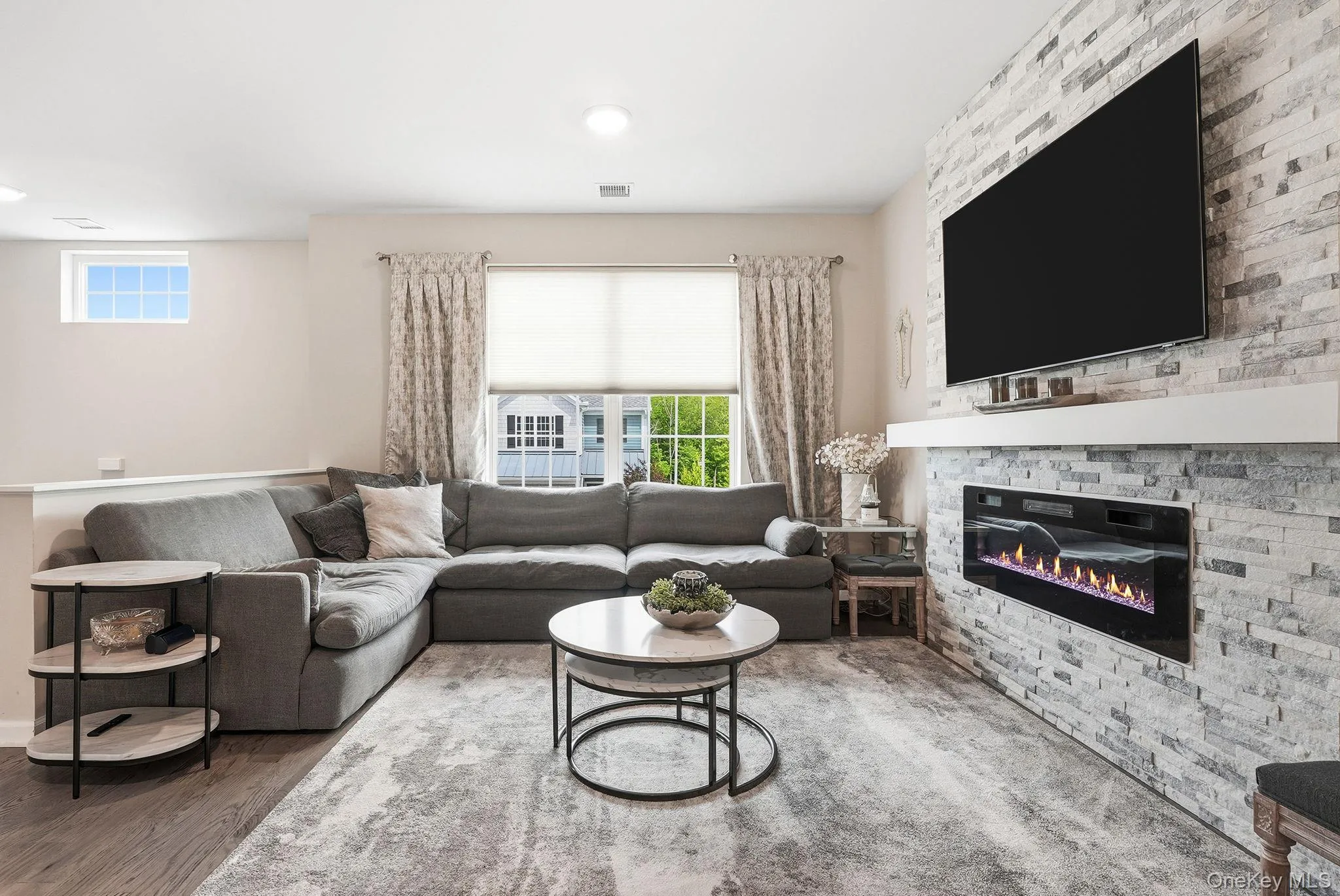 Living area featuring a textured stone-finish accent wall with an integrated electric fireplace and mantel Living area featuring a textured stone-finish accent wall with an integrated electric fireplace and mantel