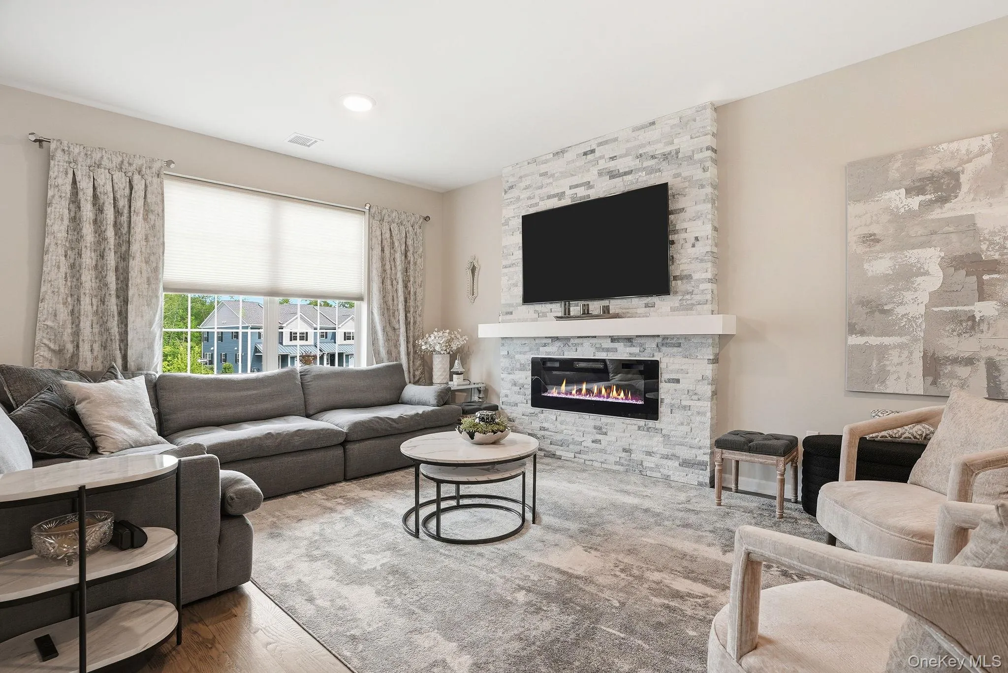 Living area featuring a stone accent wall with an inset electric fireplace and wood-finish flooring Living area featuring a stone accent wall with an inset electric fireplace and wood-finish flooring