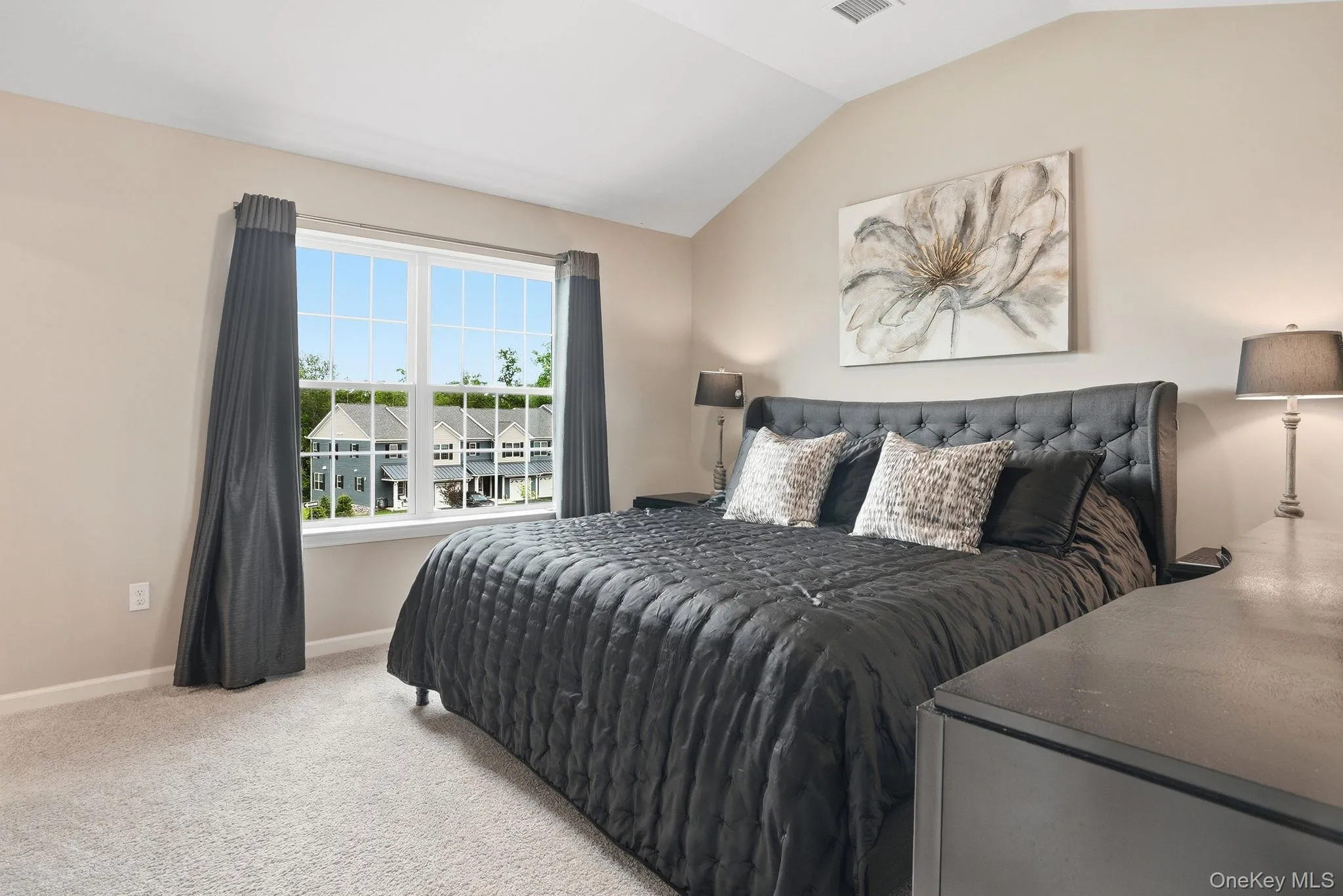 Primary bedroom featuring featuring vaulted ceilings, neutral-toned walls, and plush carpet flooring Primary bedroom featuring featuring vaulted ceilings, neutral-toned walls, and plush carpet flooring