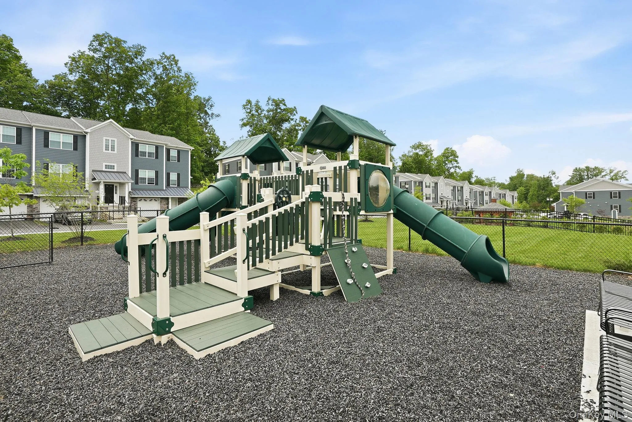 Outdoor play structure featuring multiple slides, climbing elements, and protective ground surfacing Outdoor play structure featuring multiple slides, climbing elements, and protective ground surfacing