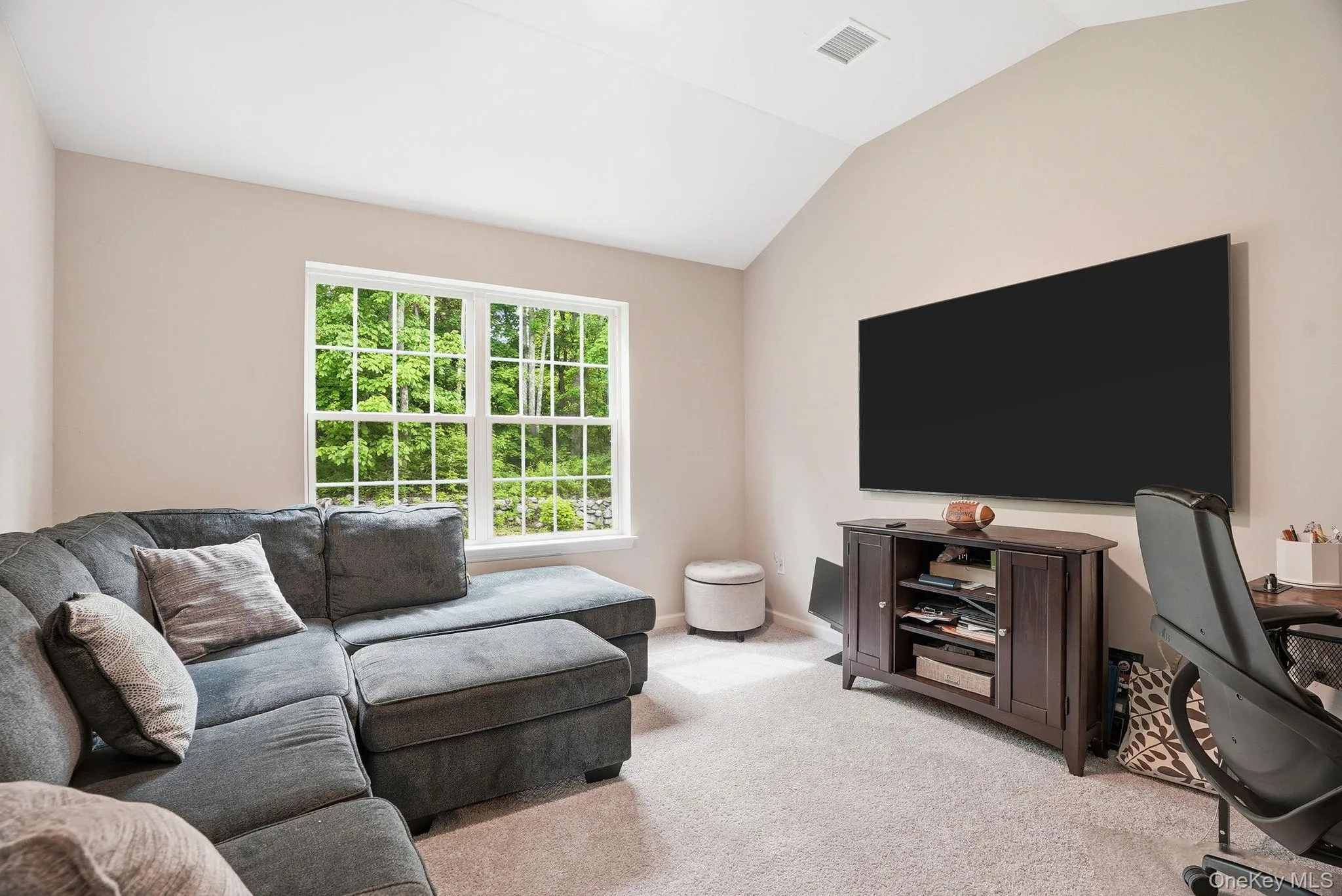 Flex space - potential 3rd bedroom or office with vaulted ceiling room featuring a double window, wall-mounted display, and light-colored carpet flooring Flex space - potential 3rd bedroom or office with vaulted ceiling room featuring a double window, wall-mounted display, and light-colored carpet flooring