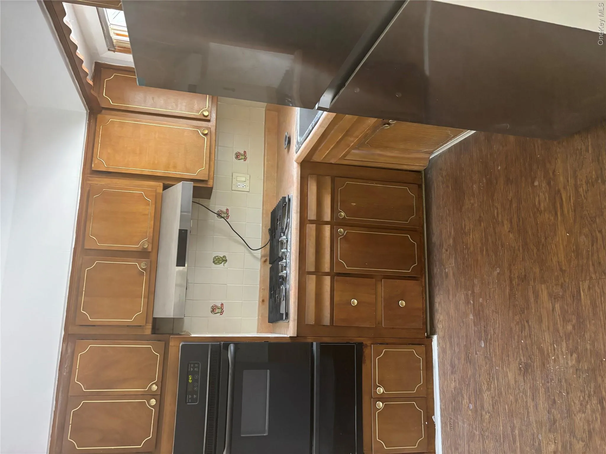 Kitchen featuring wood-finish cabinetry, a black double wall oven, a black gas cooktop, a stainless steel range hood, and tile backsplash Kitchen featuring wood-finish cabinetry, a black double wall oven, a black gas cooktop, a stainless steel range hood, and tile backsplash