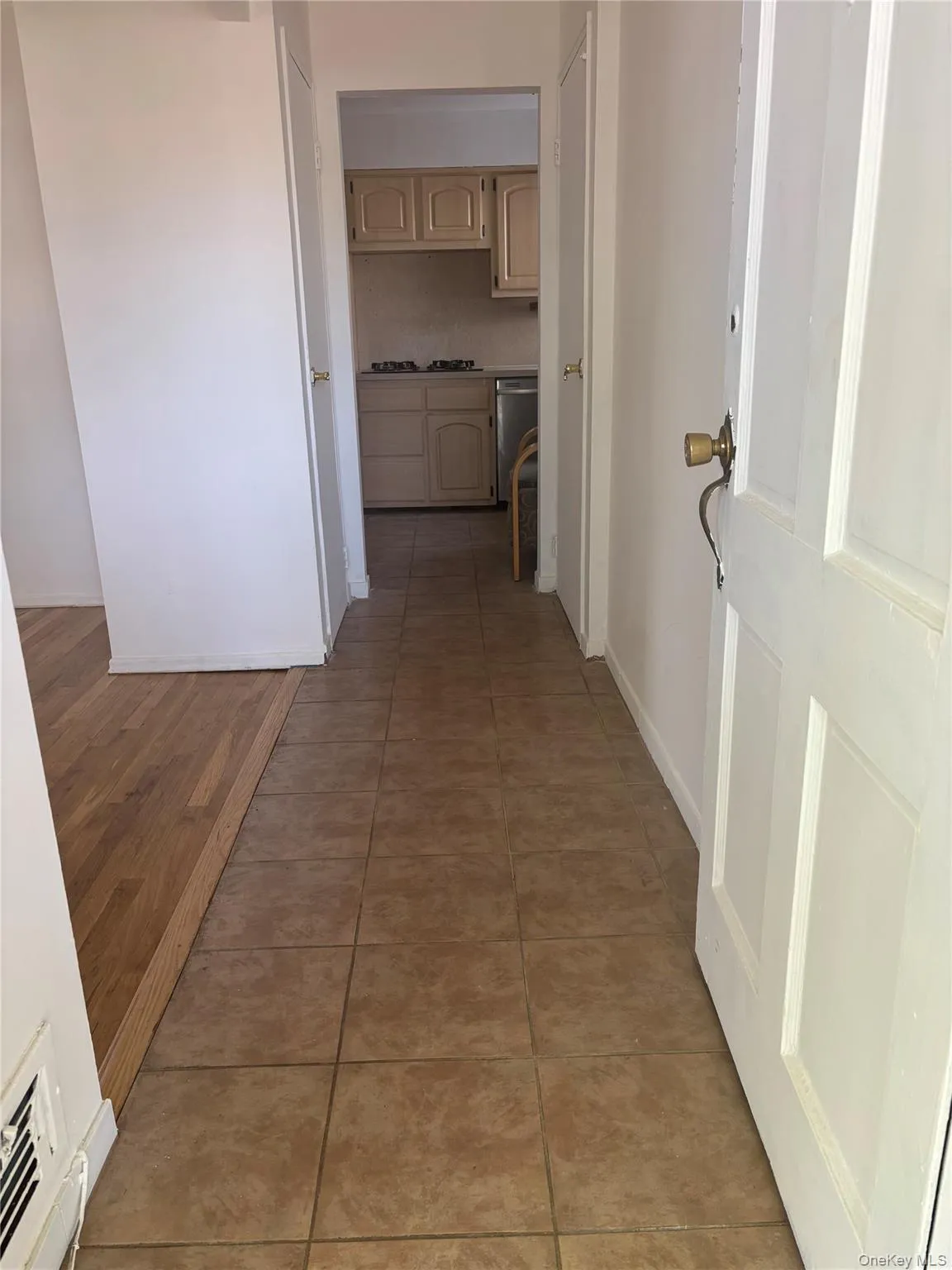 Tiled entryway with wood-finish flooring extending into an adjacent area Tiled entryway with wood-finish flooring extending into an adjacent area