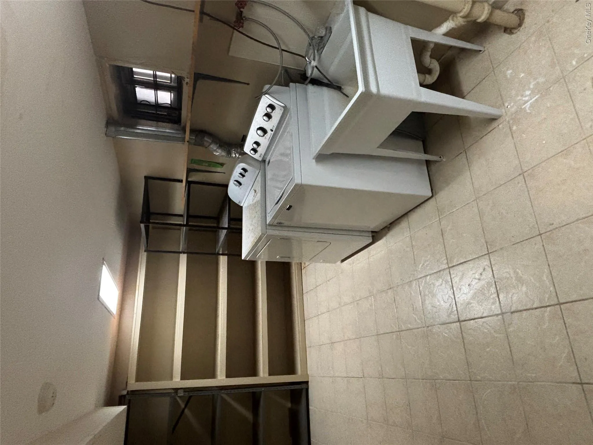 Laundry area featuring light-toned tile flooring, built-in shelving, and an integrated utility sink Laundry area featuring light-toned tile flooring, built-in shelving, and an integrated utility sink