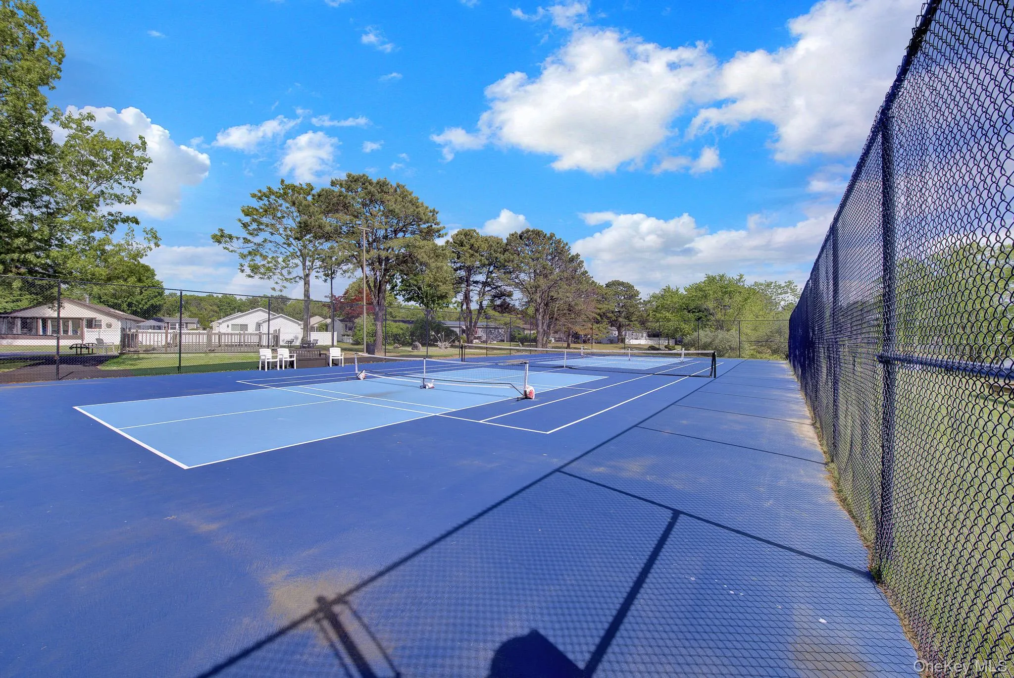 Dual blue-surfaced sports courts featuring perimeter fencing and court lines Dual blue-surfaced sports courts featuring perimeter fencing and court lines