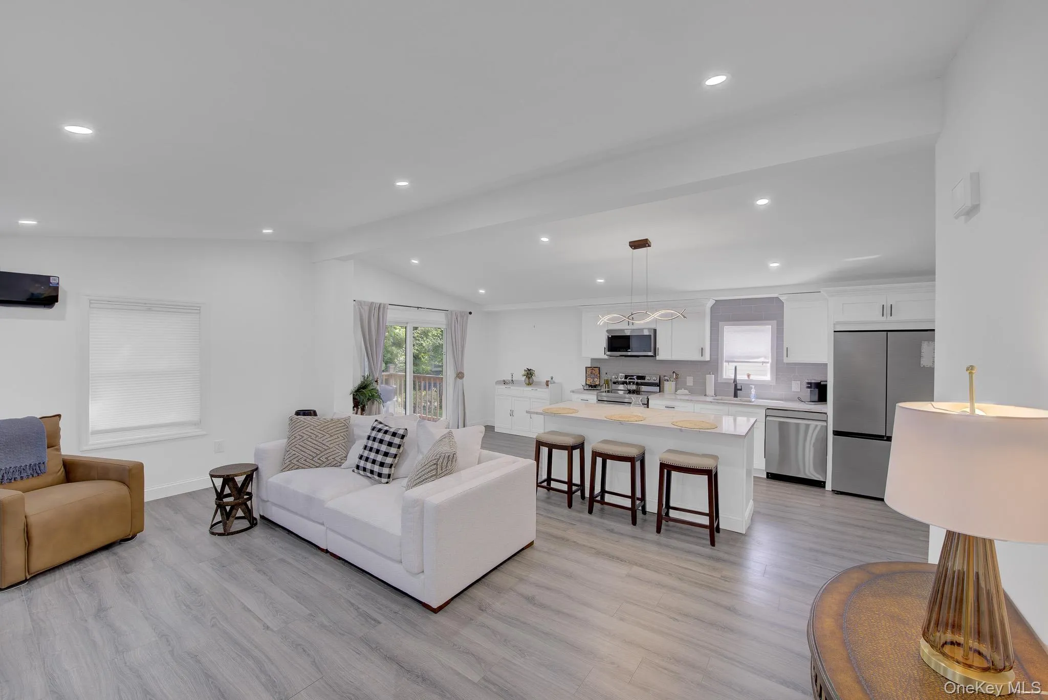 Open-concept living area with wood-finish flooring and recessed lighting Open-concept living area with wood-finish flooring and recessed lighting