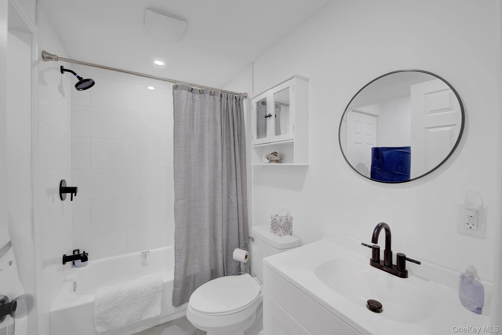 Bathroom featuring a white subway tile tub surround, dark bronze shower fixtures, and a vanity with a rectangular basin sink and dark bronze faucet Bathroom featuring a white subway tile tub surround, dark bronze shower fixtures, and a vanity with a rectangular basin sink and dark bronze faucet