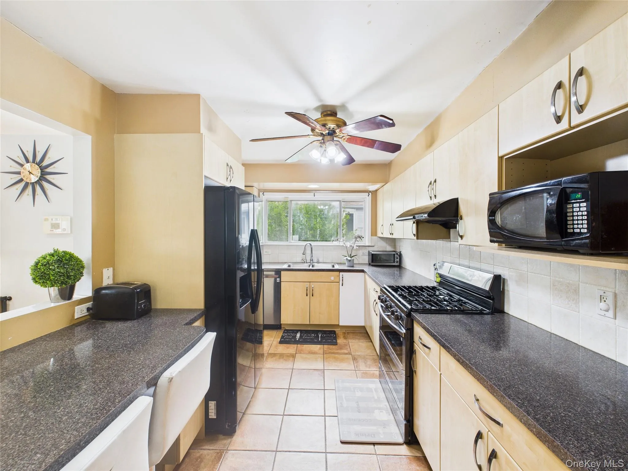 Kitchen with black appliances, a sink, backsplash, and light brown cabinets Kitchen with black appliances, a sink, backsplash, and light brown cabinets