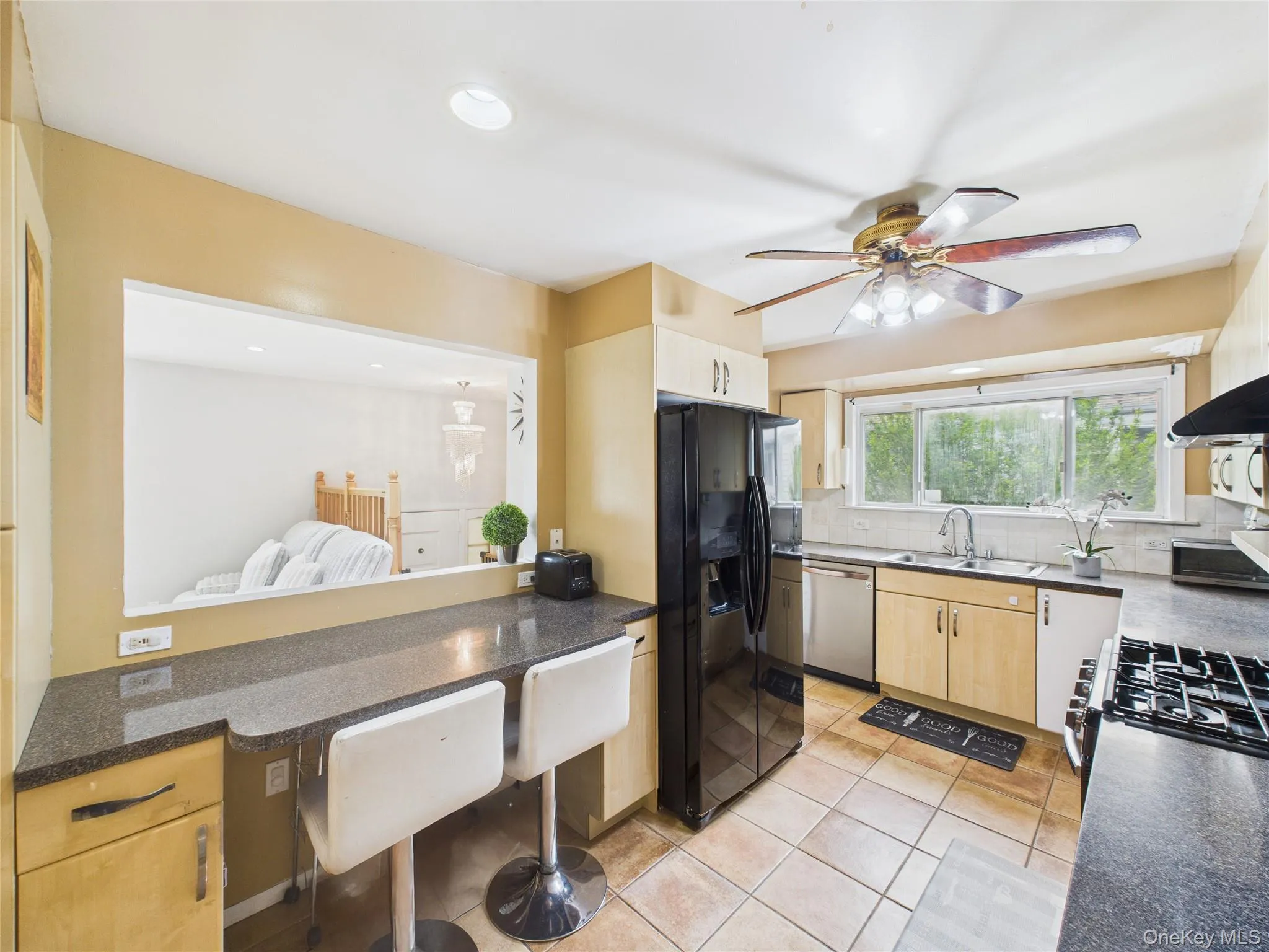 Kitchen with black refrigerator with ice dispenser, dishwasher, a sink, a ceiling fan, and tasteful backsplash Kitchen with black refrigerator with ice dispenser, dishwasher, a sink, a ceiling fan, and tasteful backsplash