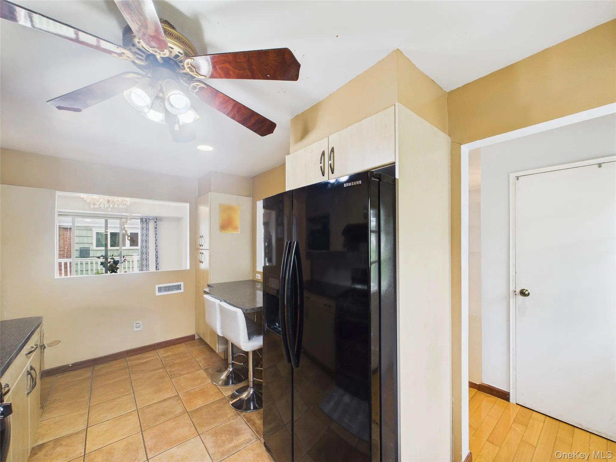 Kitchen with black refrigerator with ice dispenser, dark countertops, a ceiling fan, and baseboards Kitchen with black refrigerator with ice dispenser, dark countertops, a ceiling fan, and baseboards