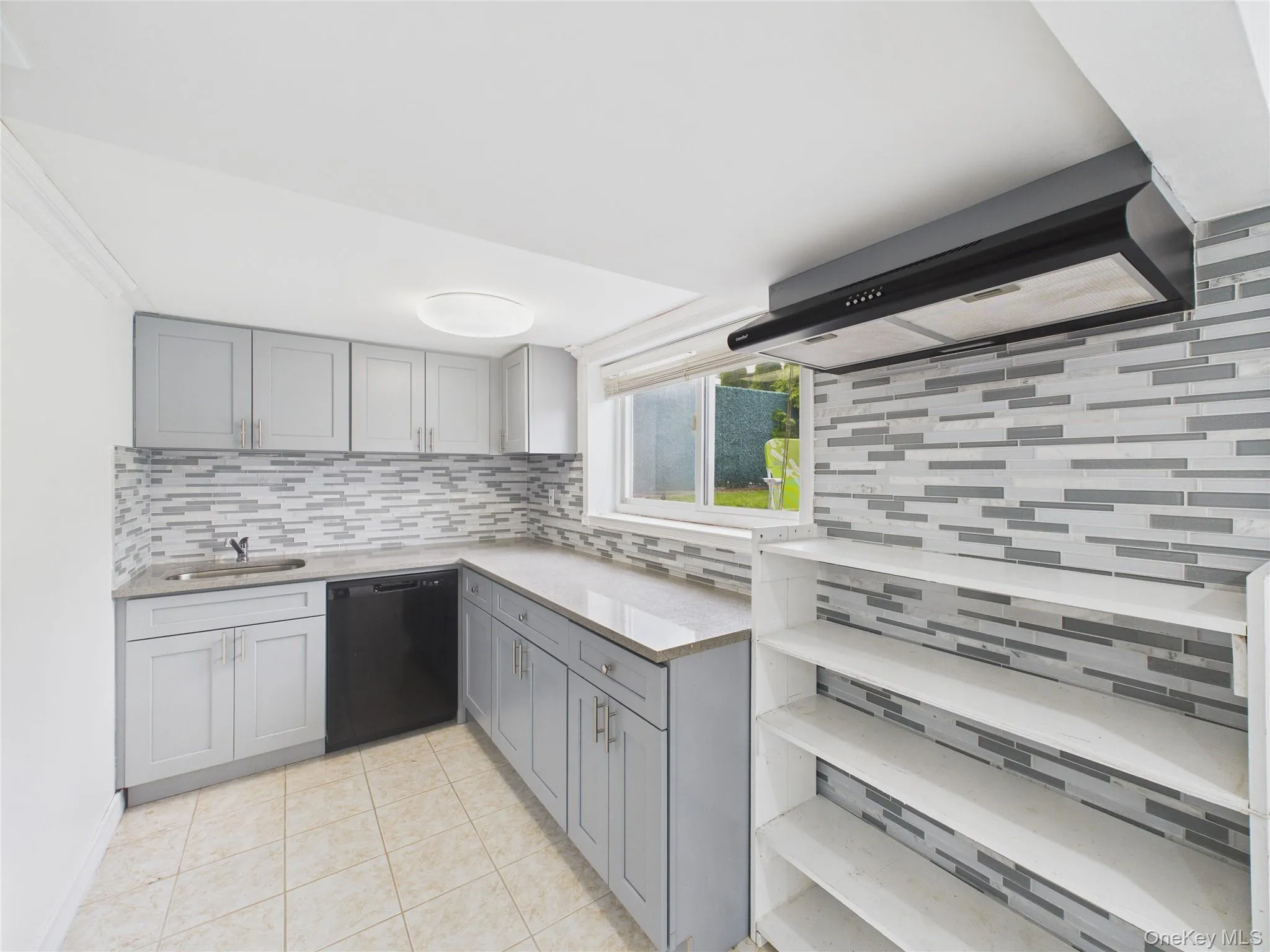 Kitchen featuring dishwashing machine, gray cabinetry, decorative backsplash, and light tile patterned floors Kitchen featuring dishwashing machine, gray cabinetry, decorative backsplash, and light tile patterned floors