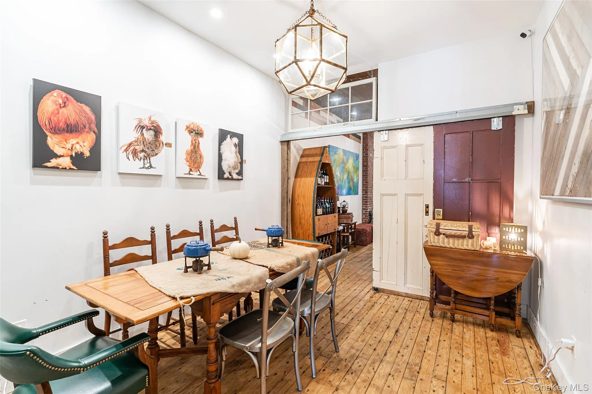 Dining room with an inviting chandelier, a towering ceiling, and light hardwood / wood-style flooring Dining room with an inviting chandelier, a towering ceiling, and light hardwood / wood-style flooring