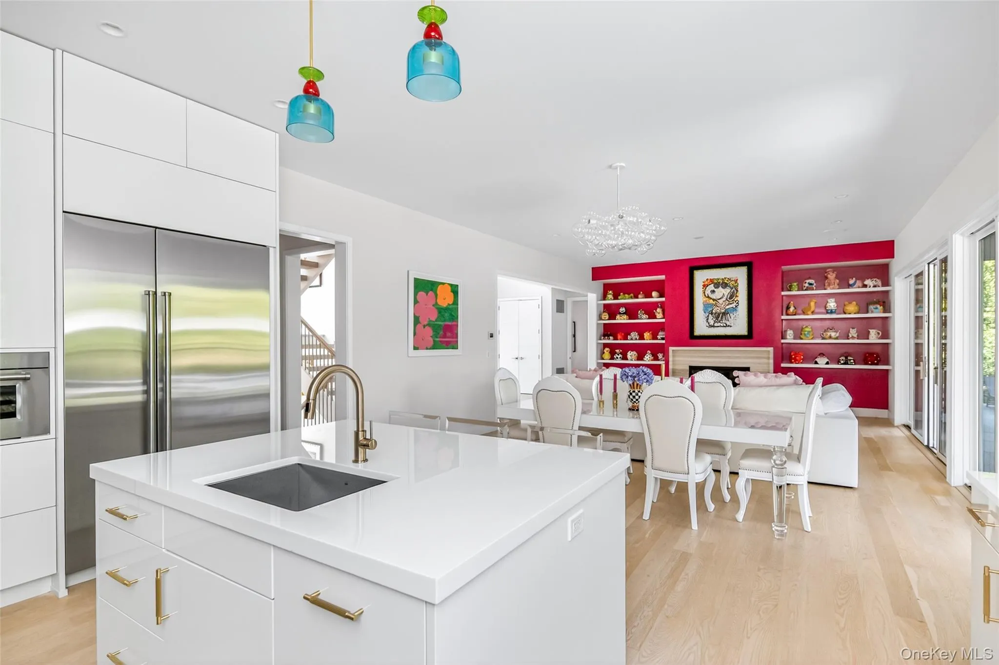 Kitchen island with integrated sink and brass-finish faucet, featuring white cabinetry and light wood-finish flooring Kitchen island with integrated sink and brass-finish faucet, featuring white cabinetry and light wood-finish flooring