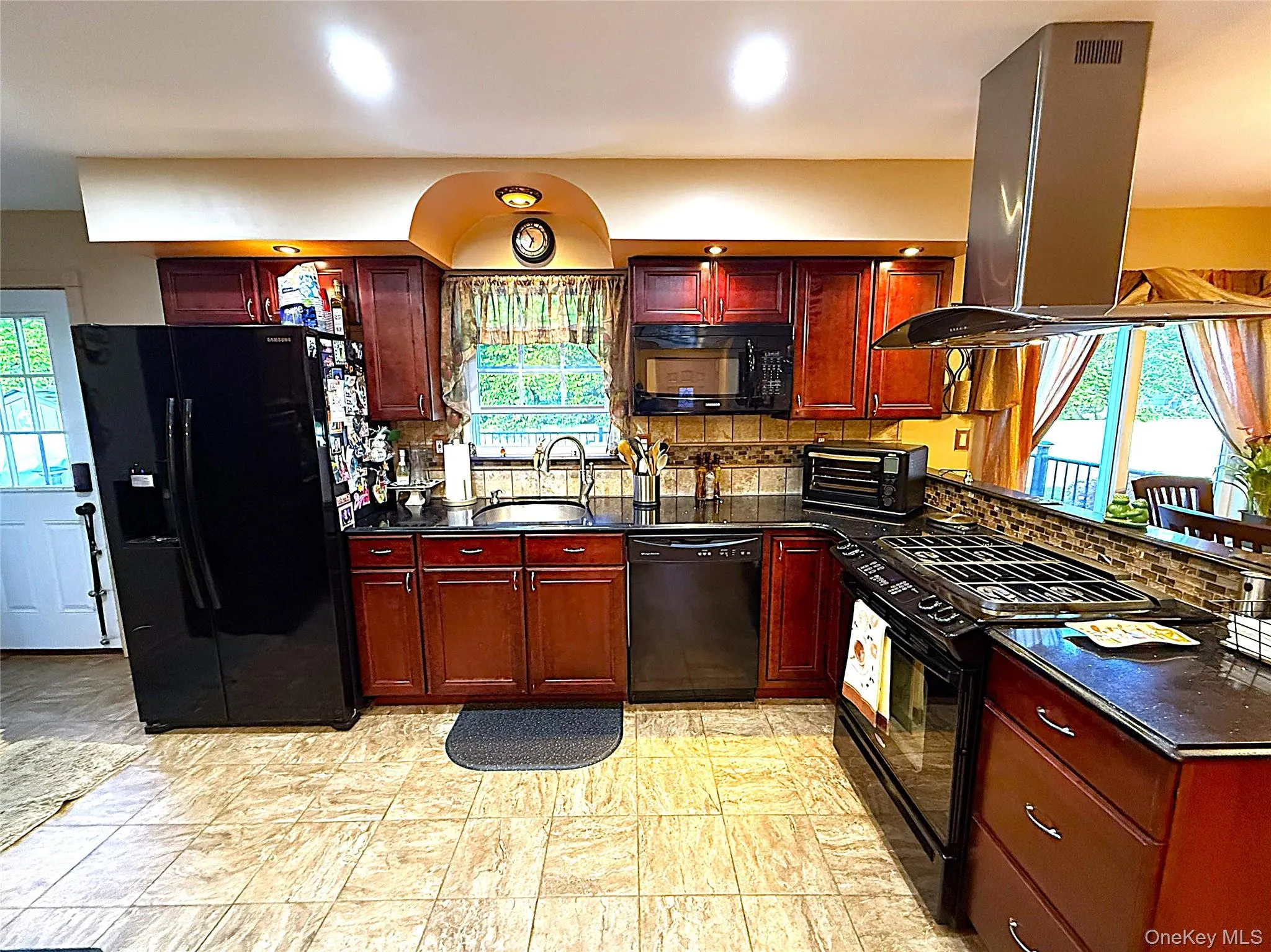 Kitchen featuring wood-finish cabinetry and a mosaic tile backsplash Kitchen featuring wood-finish cabinetry and a mosaic tile backsplash