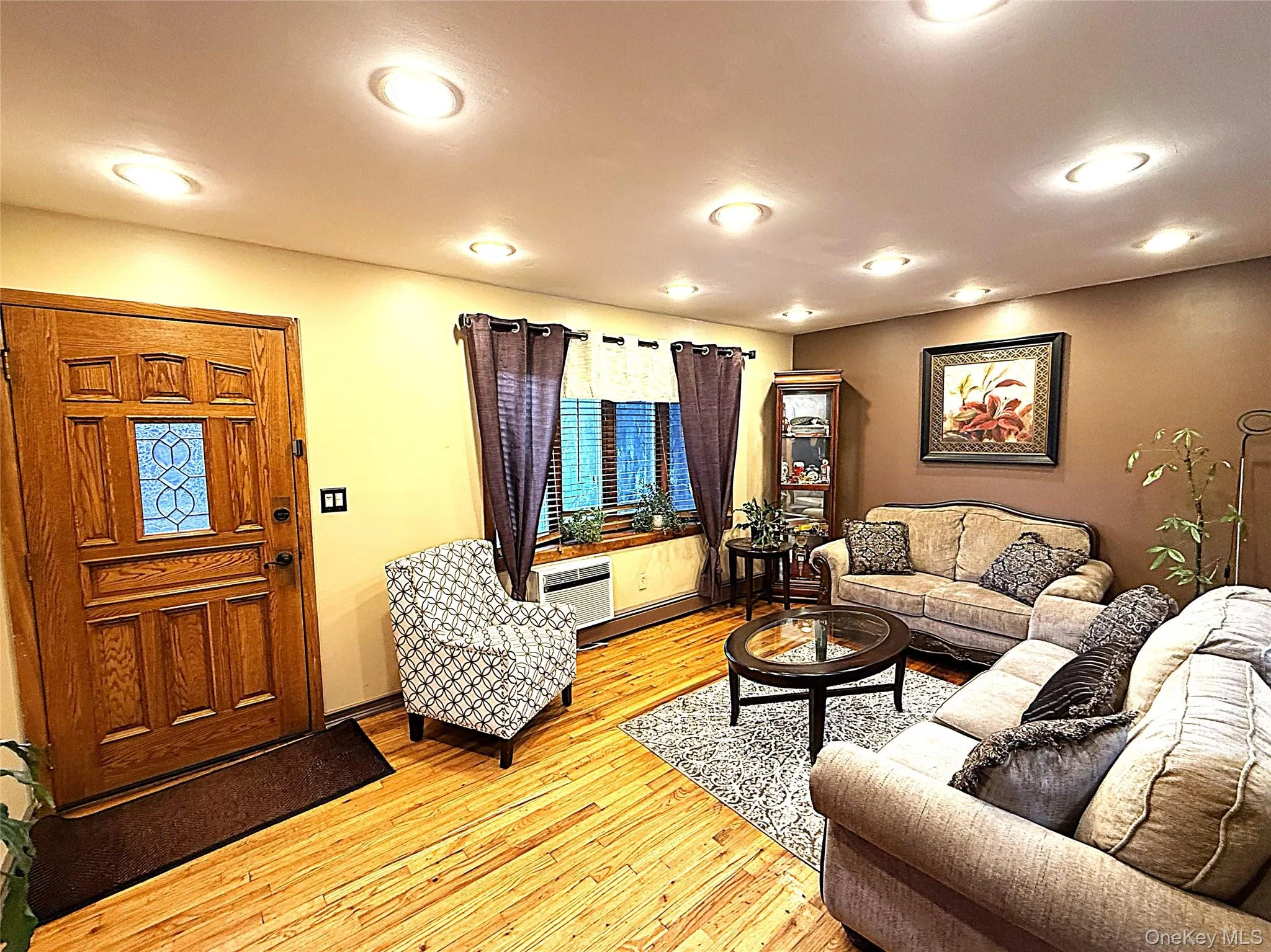 Living area featuring wood-finish flooring, recessed lighting, and a paneled entry door with decorative glass Living area featuring wood-finish flooring, recessed lighting, and a paneled entry door with decorative glass