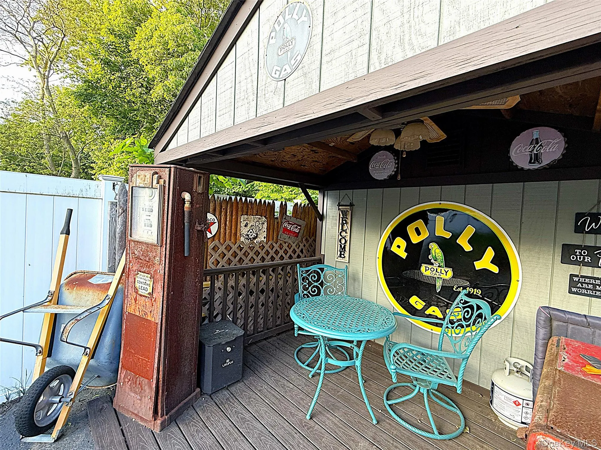Wood-finish decking with an overhead shelter, featuring a slatted wood wall and a decorative metal sign Wood-finish decking with an overhead shelter, featuring a slatted wood wall and a decorative metal sign