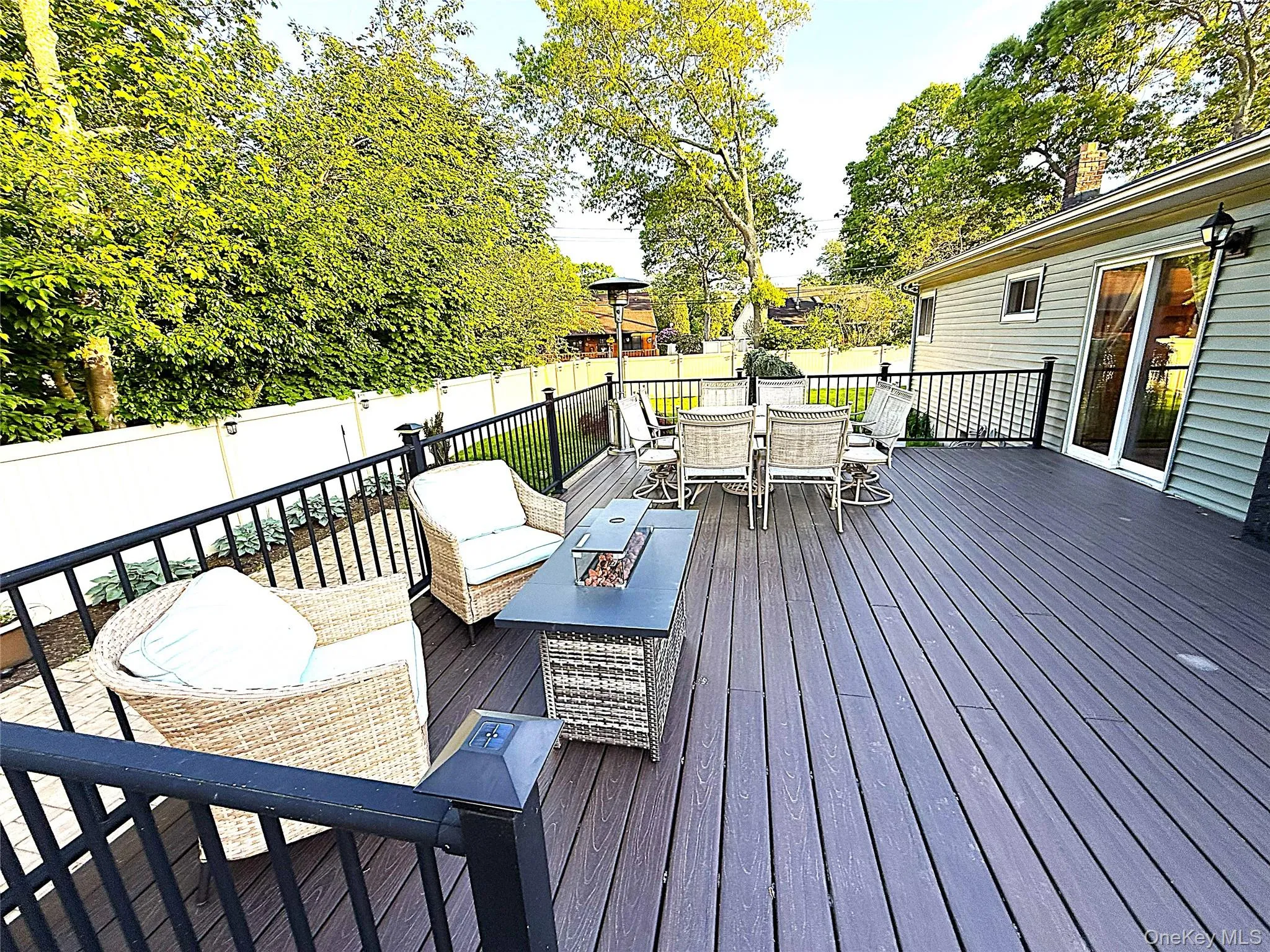 Spacious outdoor deck featuring composite decking, black aluminum railings with glass panel accents, and a privacy fence Spacious outdoor deck featuring composite decking, black aluminum railings with glass panel accents, and a privacy fence