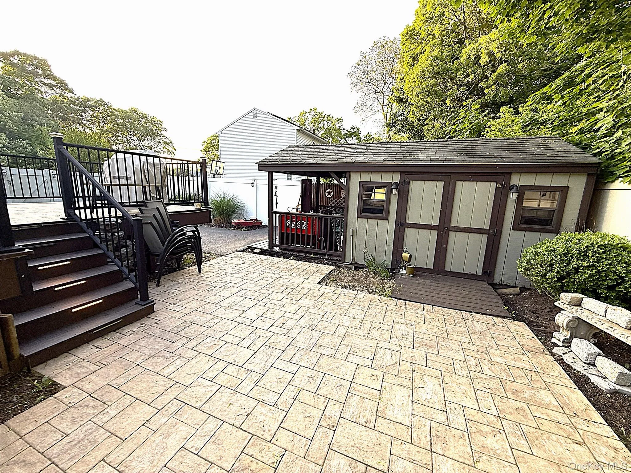 Expansive patterned patio with a wood-finish deck featuring dark railings Expansive patterned patio with a wood-finish deck featuring dark railings
