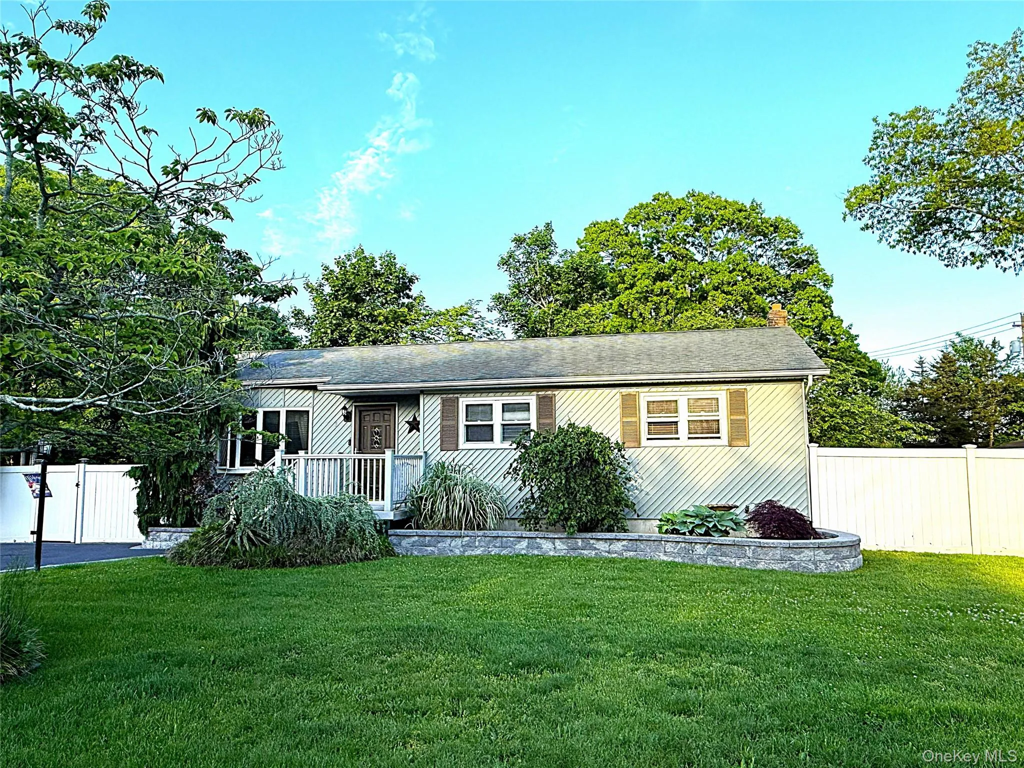 Ranch-style residence featuring horizontal siding, a gabled roofline, and a prominent front entrance with a porch Ranch-style residence featuring horizontal siding, a gabled roofline, and a prominent front entrance with a porch