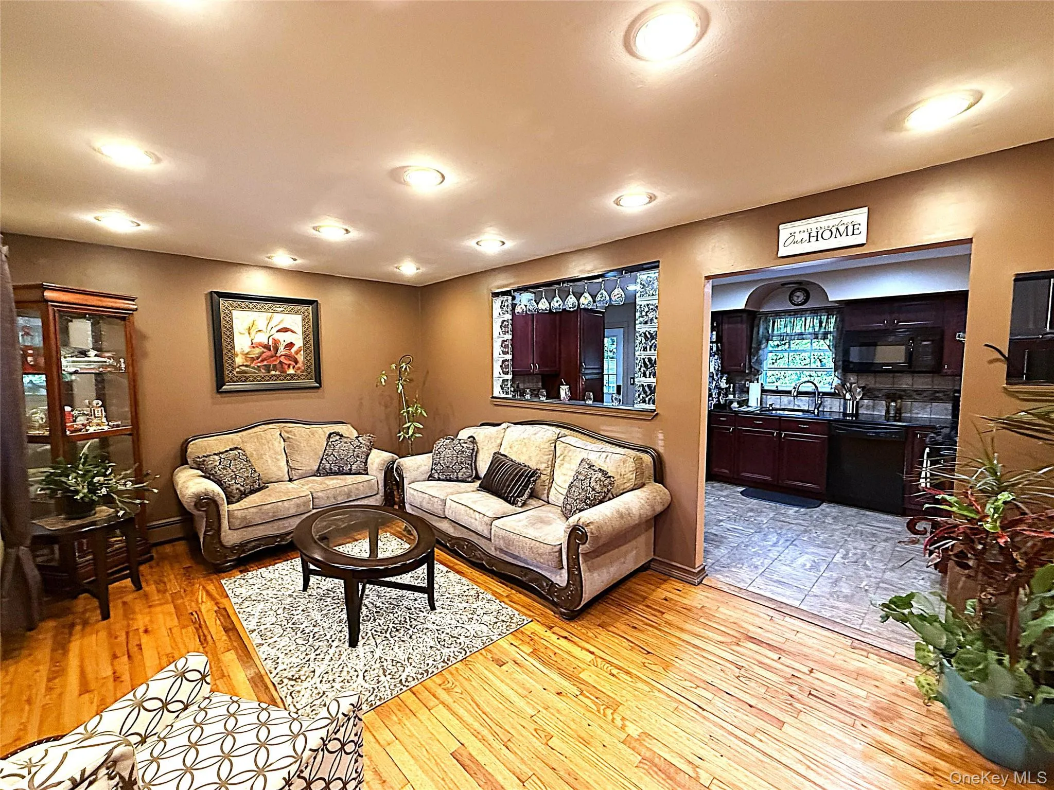 Living area featuring wood-finish flooring, recessed lighting, and a pass-through window to the kitchen Living area featuring wood-finish flooring, recessed lighting, and a pass-through window to the kitchen