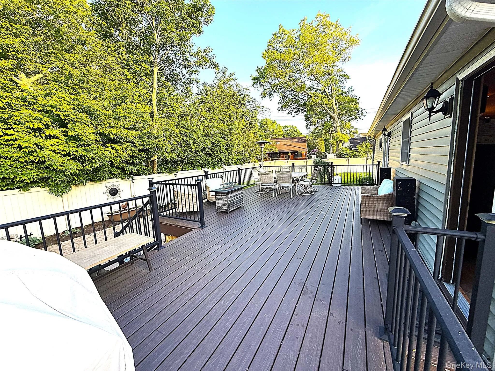Expansive multi-level composite decking featuring black metal railings, direct access to the interior, and a fenced perimeter Expansive multi-level composite decking featuring black metal railings, direct access to the interior, and a fenced perimeter