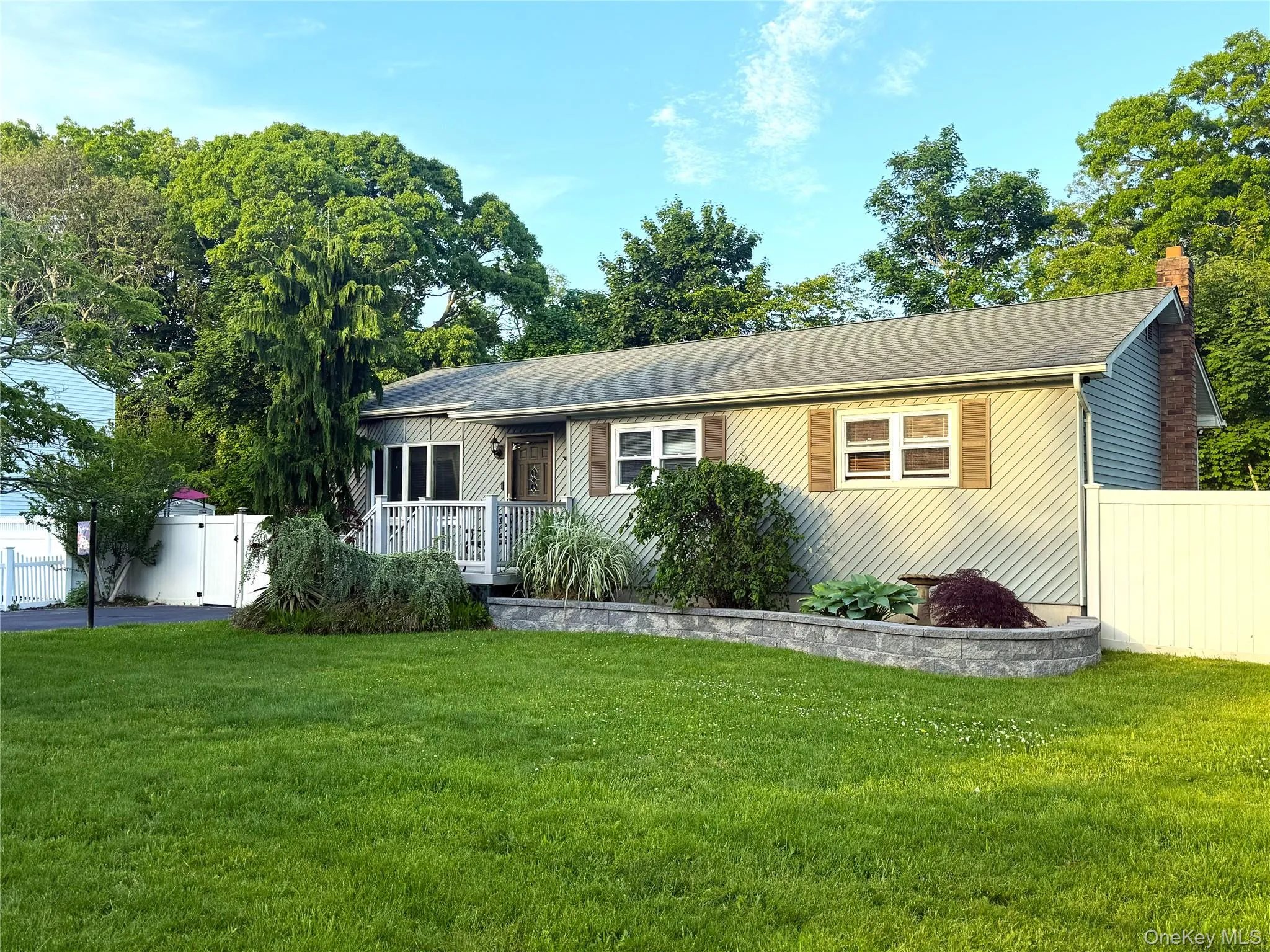 Ranch-style residence featuring horizontal siding, a gabled roof, and a brick chimney Ranch-style residence featuring horizontal siding, a gabled roof, and a brick chimney