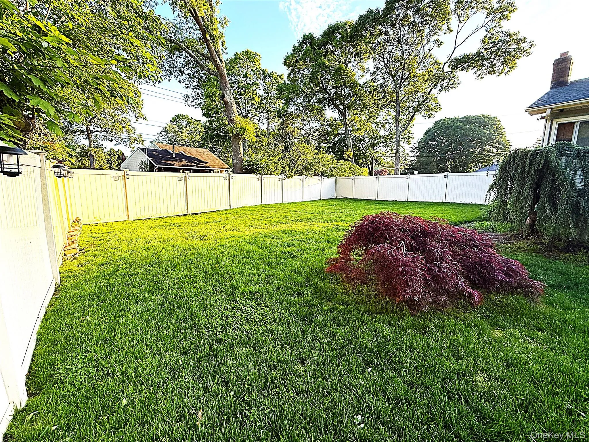 Expansive green lawn enclosed by white vinyl fencing Expansive green lawn enclosed by white vinyl fencing
