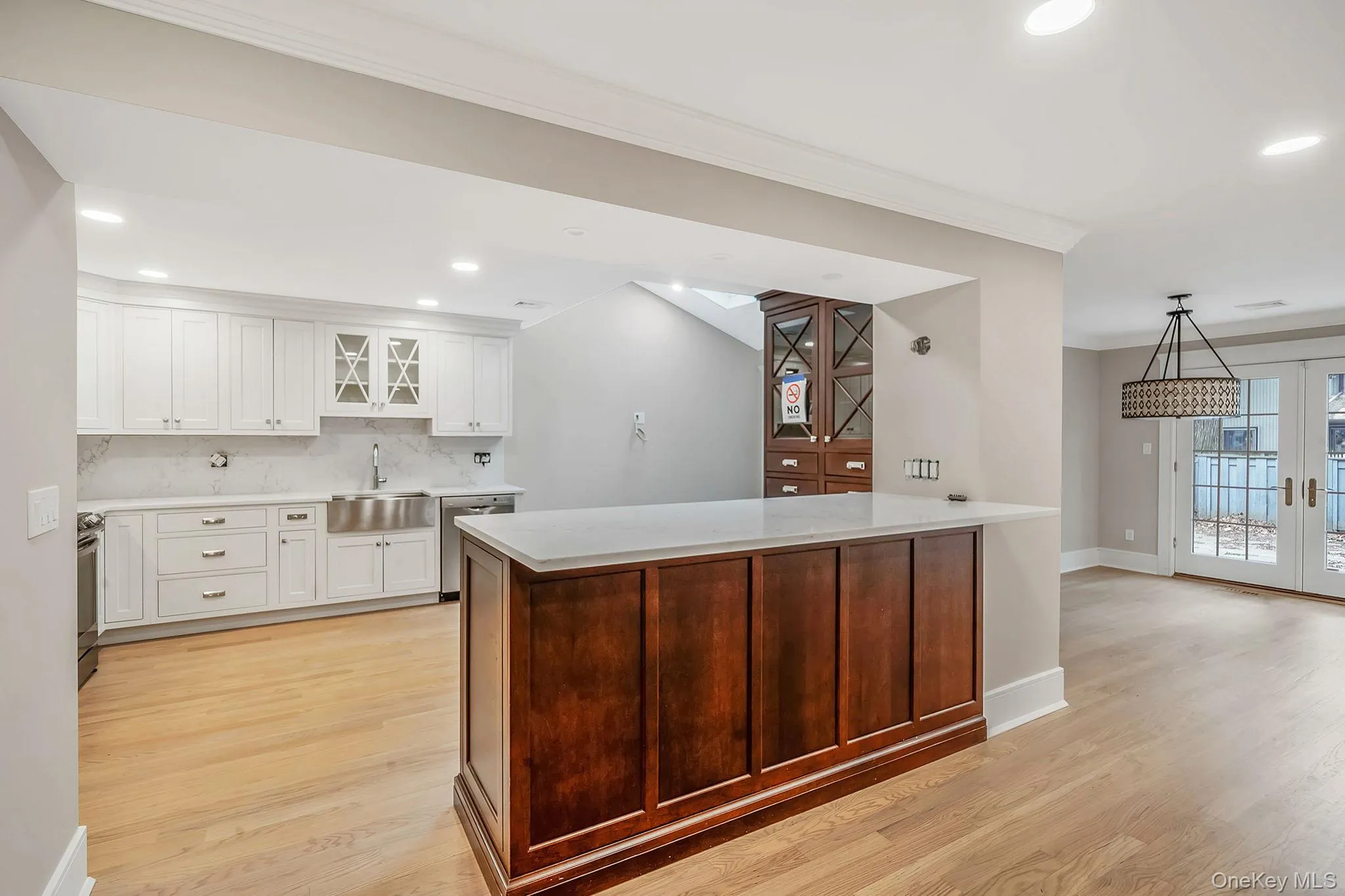 Modern kitchen featuring white shaker cabinetry, stainless steel farmhouse sink, and a contrasting dark wood island with light-colored countertops Modern kitchen featuring white shaker cabinetry, stainless steel farmhouse sink, and a contrasting dark wood island with light-colored countertops