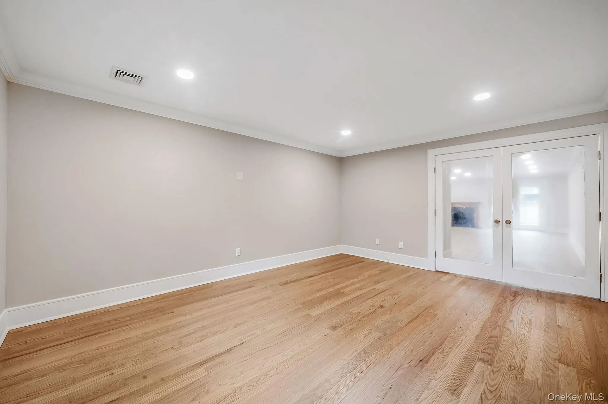 Room featuring wood-finish flooring, recessed lighting, crown molding, and a pair of French doors with frosted glass panels Room featuring wood-finish flooring, recessed lighting, crown molding, and a pair of French doors with frosted glass panels