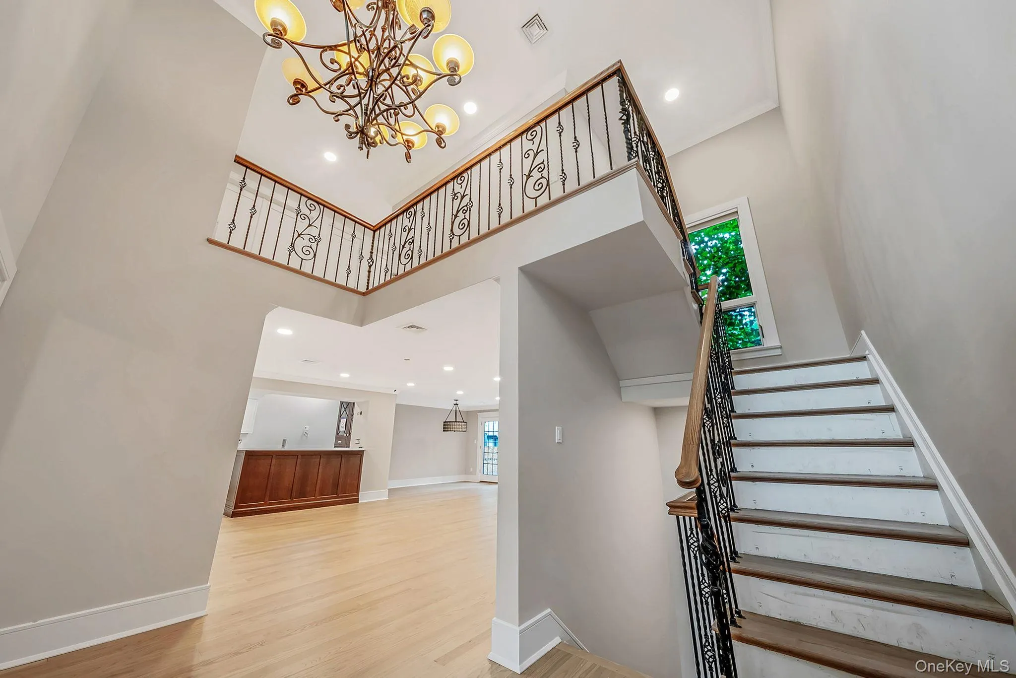 Two-story foyer featuring a grand staircase with wrought iron balusters and a wood handrail Two-story foyer featuring a grand staircase with wrought iron balusters and a wood handrail