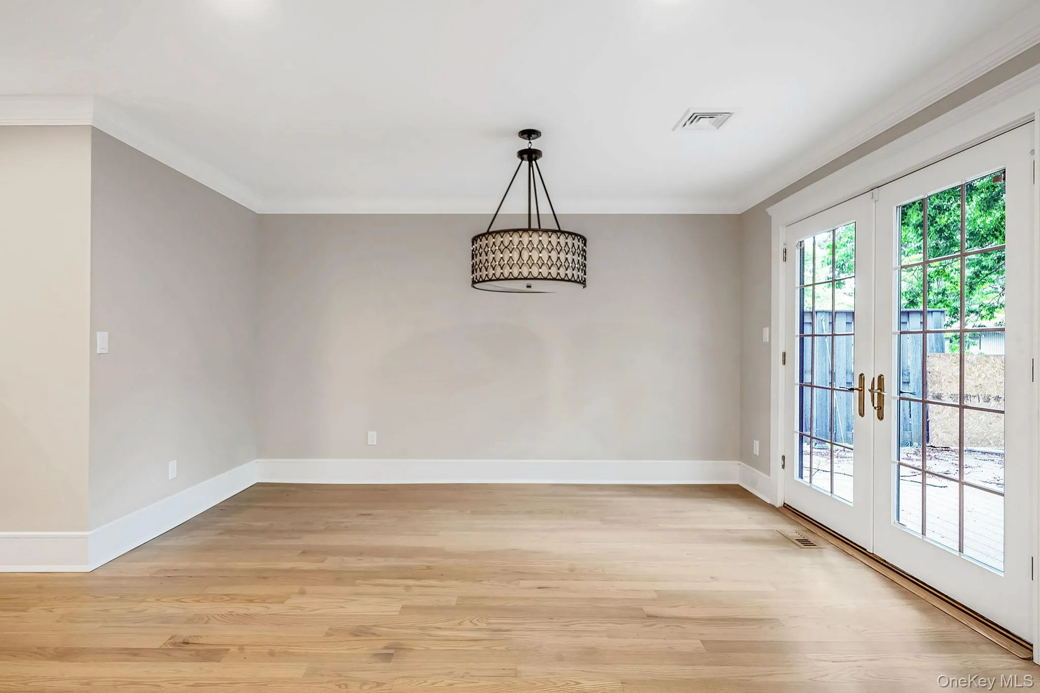 Light wood-finish flooring with crisp white baseboards and crown molding Light wood-finish flooring with crisp white baseboards and crown molding